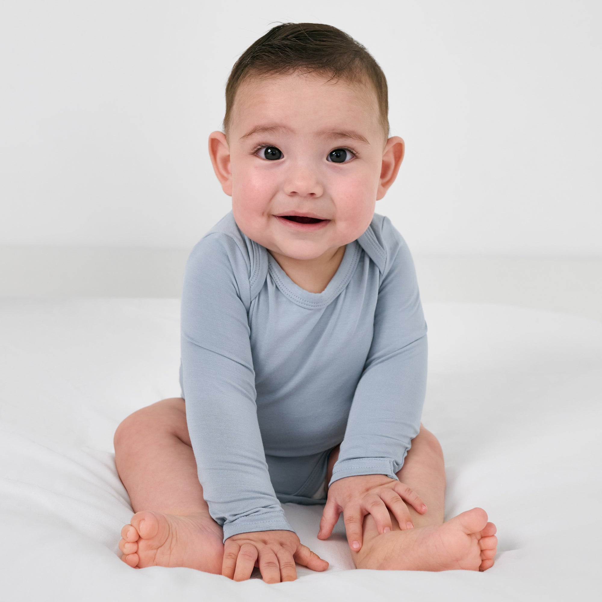 Sitting baby wearing the Fog Long Sleeve Bodysuit