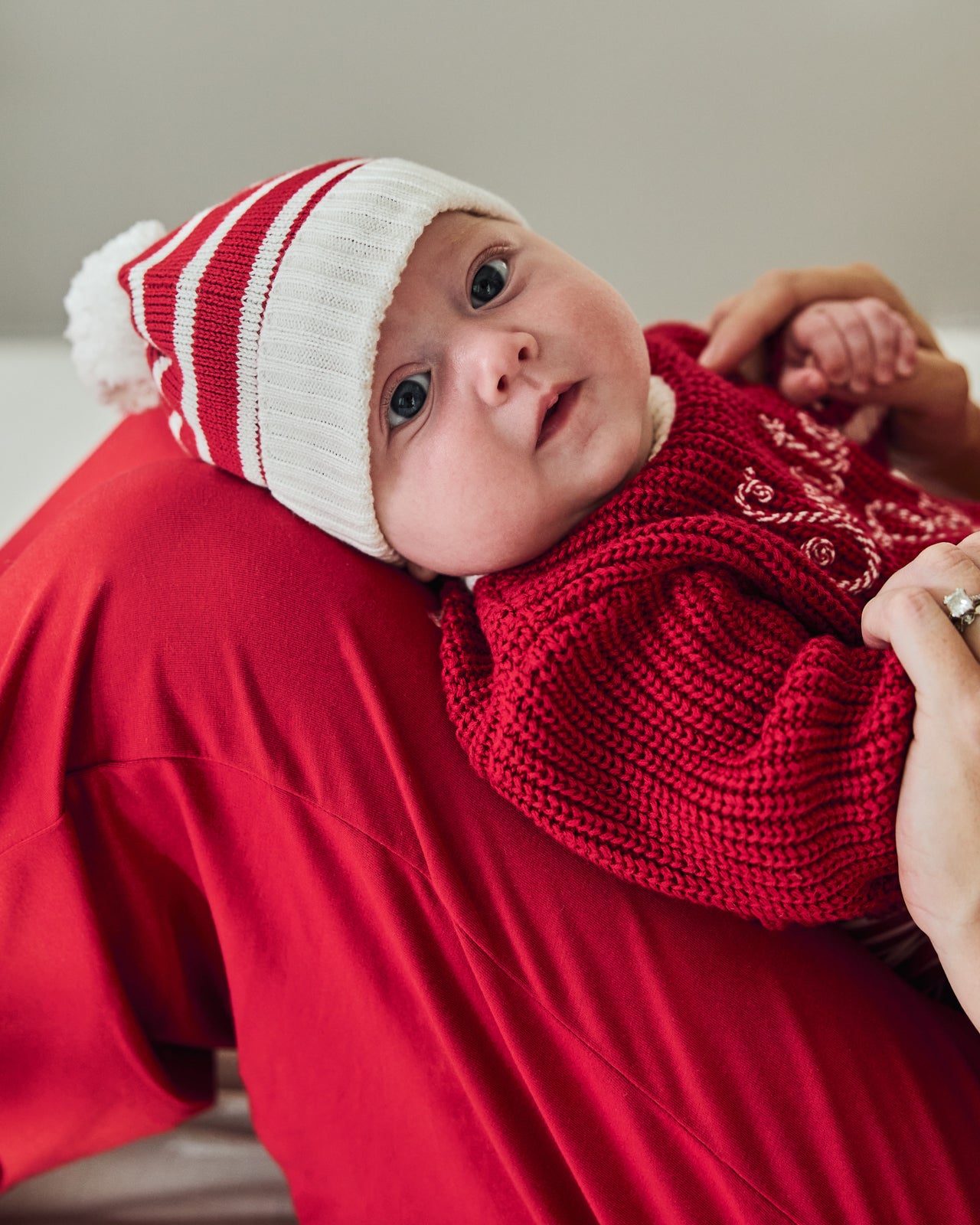 Baby wearing the Candy Cane Stripe Sweater Beanie Hat on mothers lap