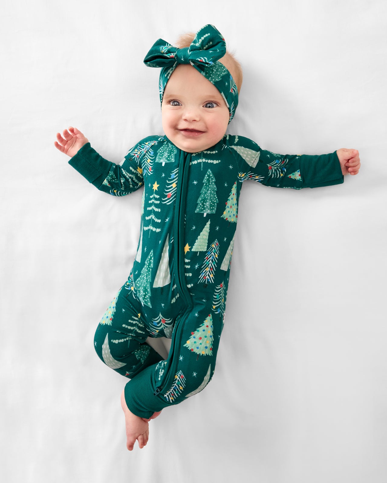 Aerial view of baby wearing the Twinkling Trees Luxe Bow Headband