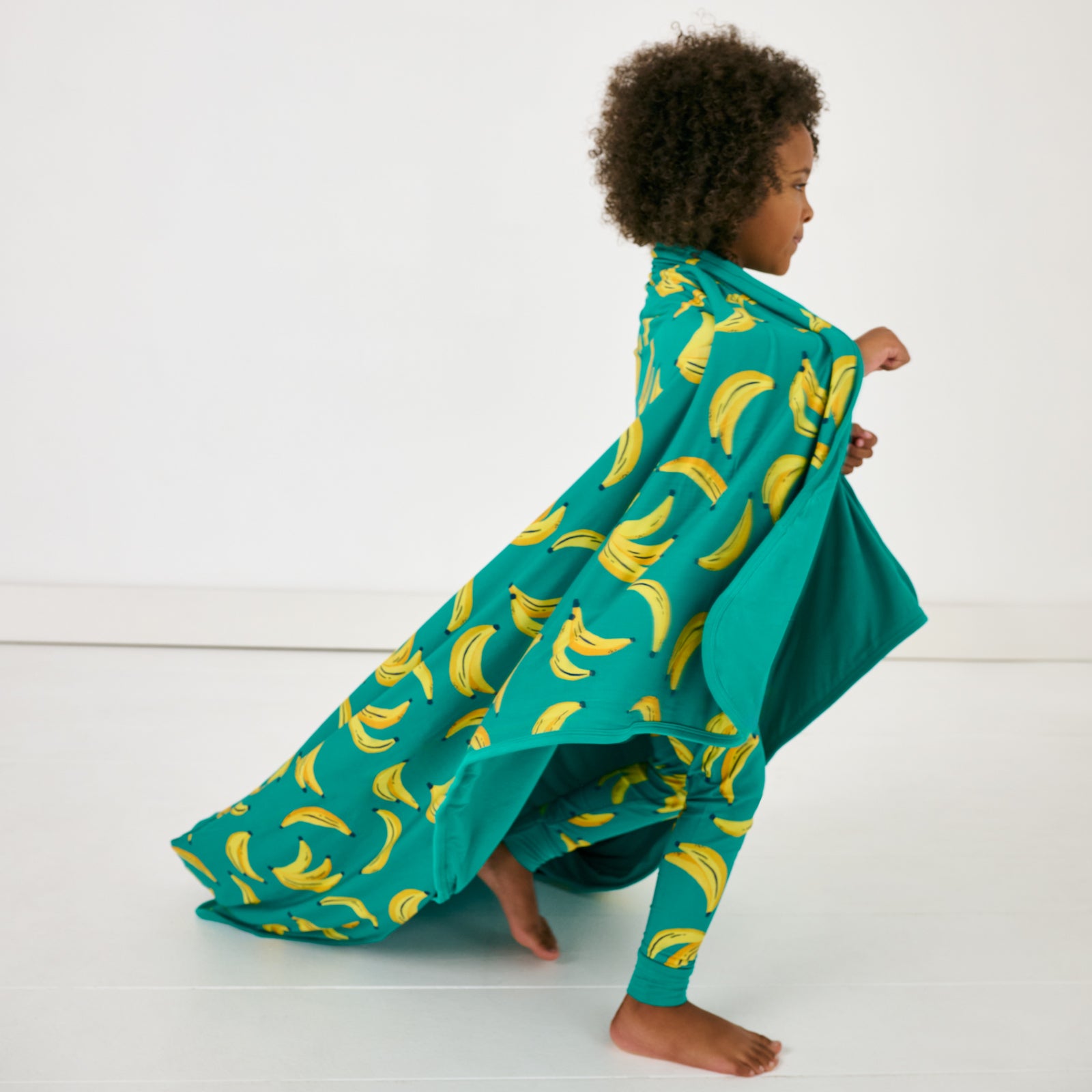 Child in motion wrapped in the Go Bananas Large Cloud Blanket®