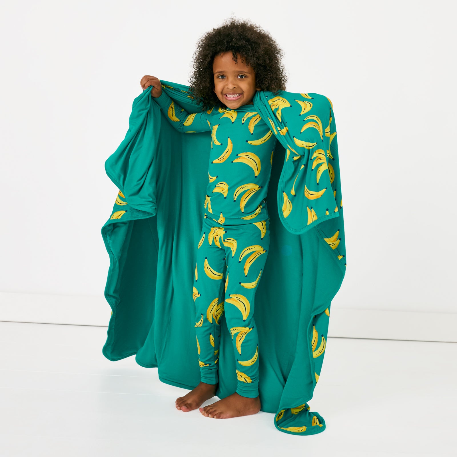 Standing child holding up the Go Bananas Large Cloud Blanket®