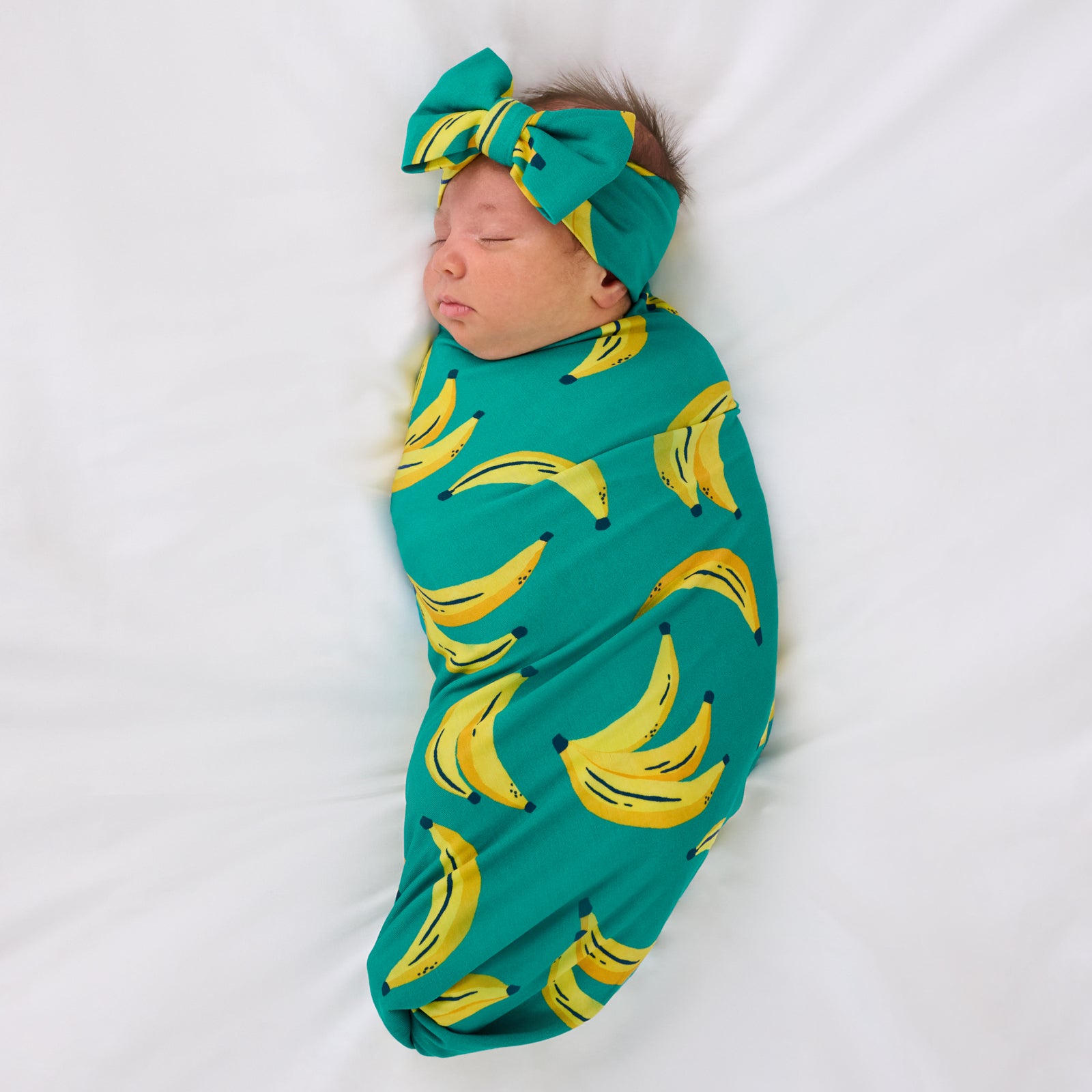 Aerial view of child wearing the Go Bananas Swaddle & Luxe Bow Headband Set
