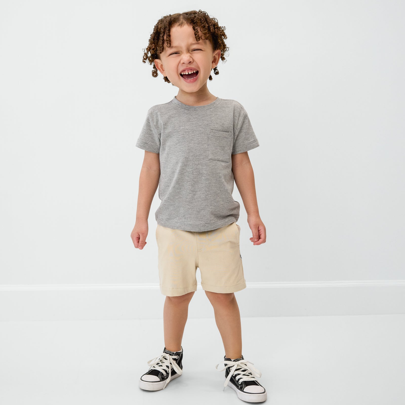 Standing child wearing the Heather Gray Relaxed Pocket Tee and light khaki chino shorts
