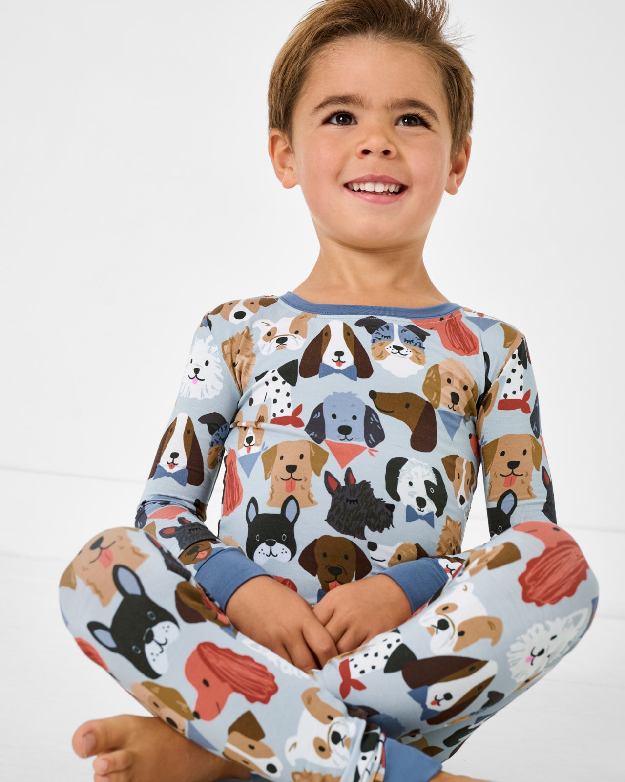 Sitting boy wearing the Gray Puppy Parade Two-Piece Pajama Set