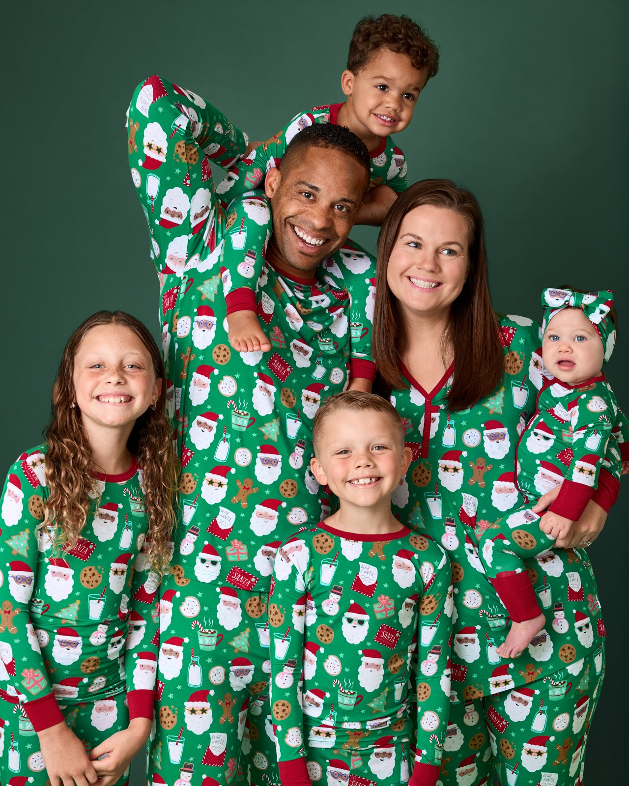 Family wearing matching Cookies for Santa pajamas on a green background
