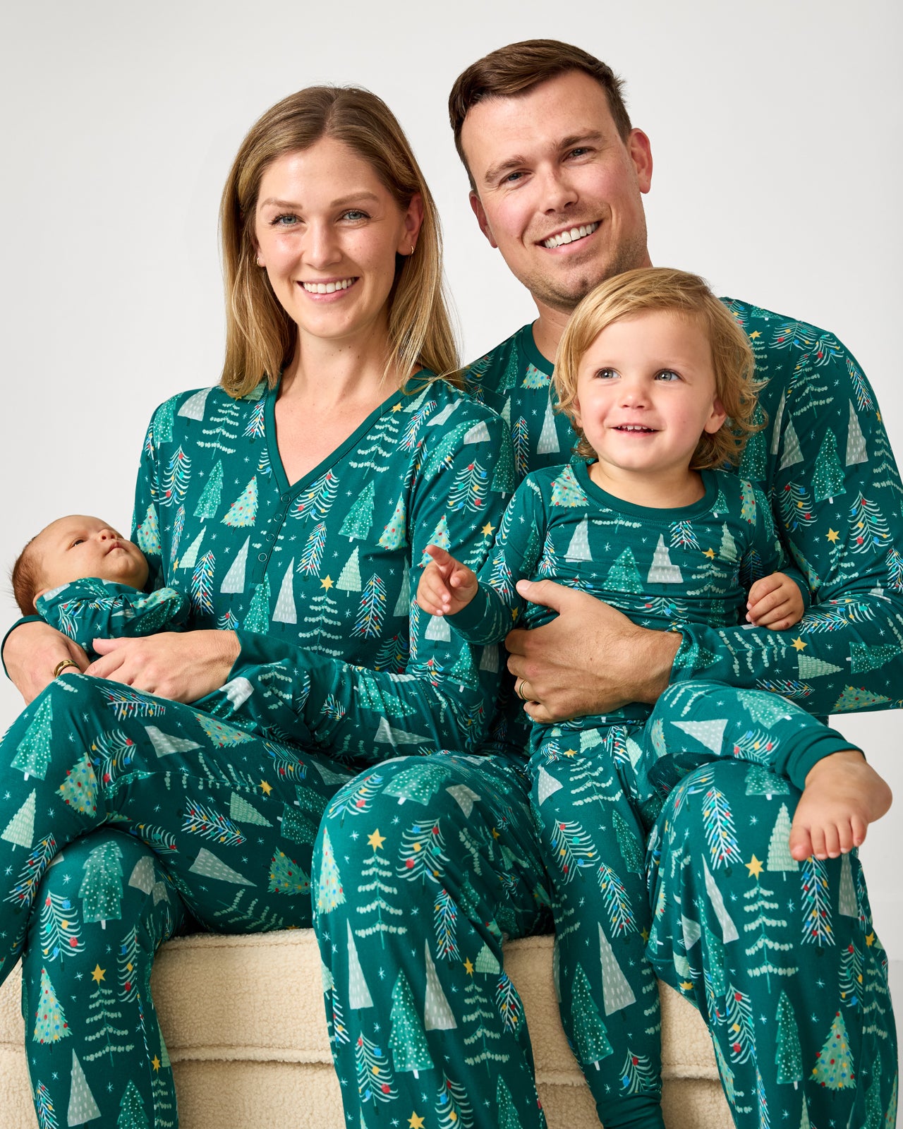 Family of four wearing matching Twinkling Trees holiday pajamas