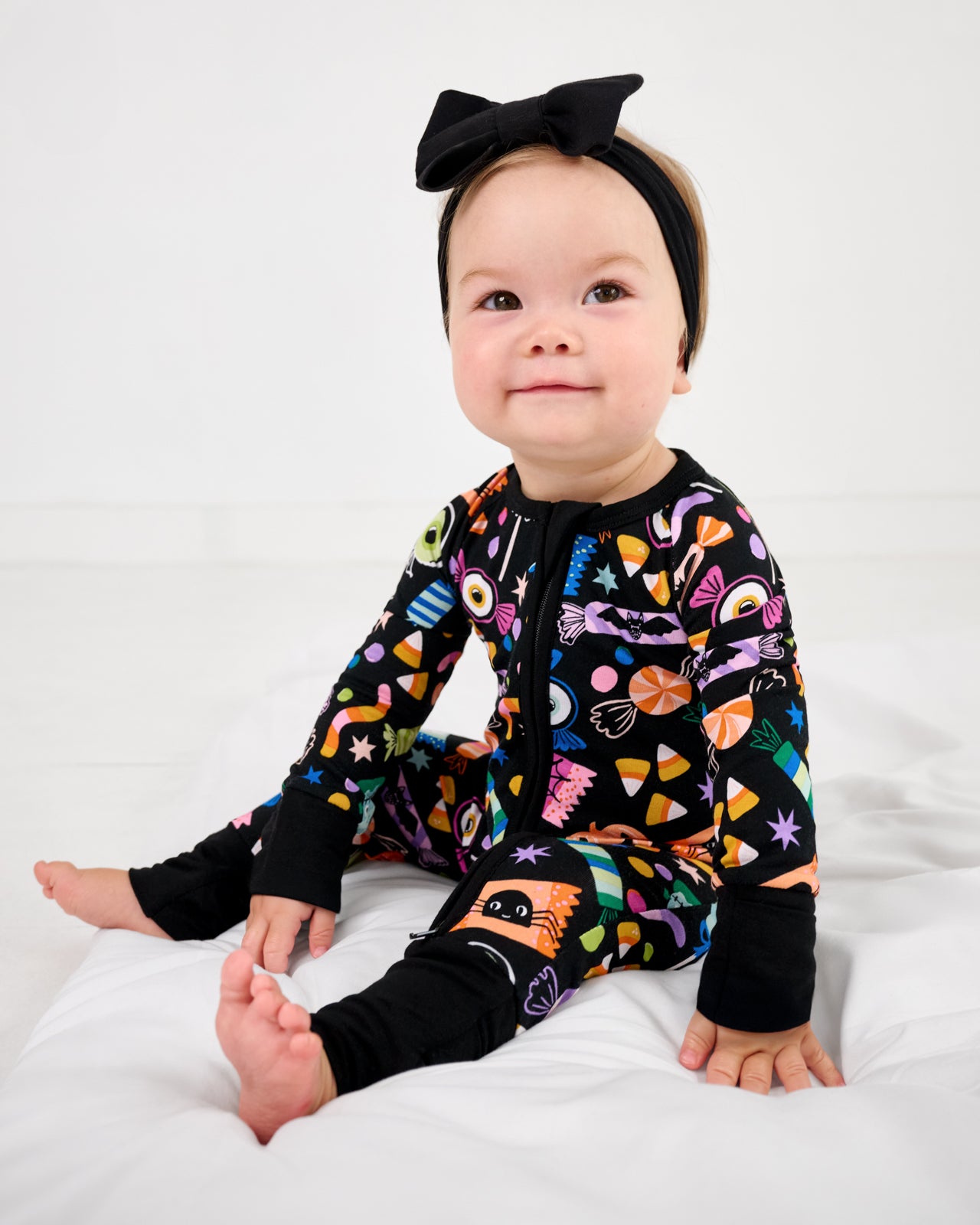 Baby wearing the Halloween Haul Zippy with a black luxe bow headband