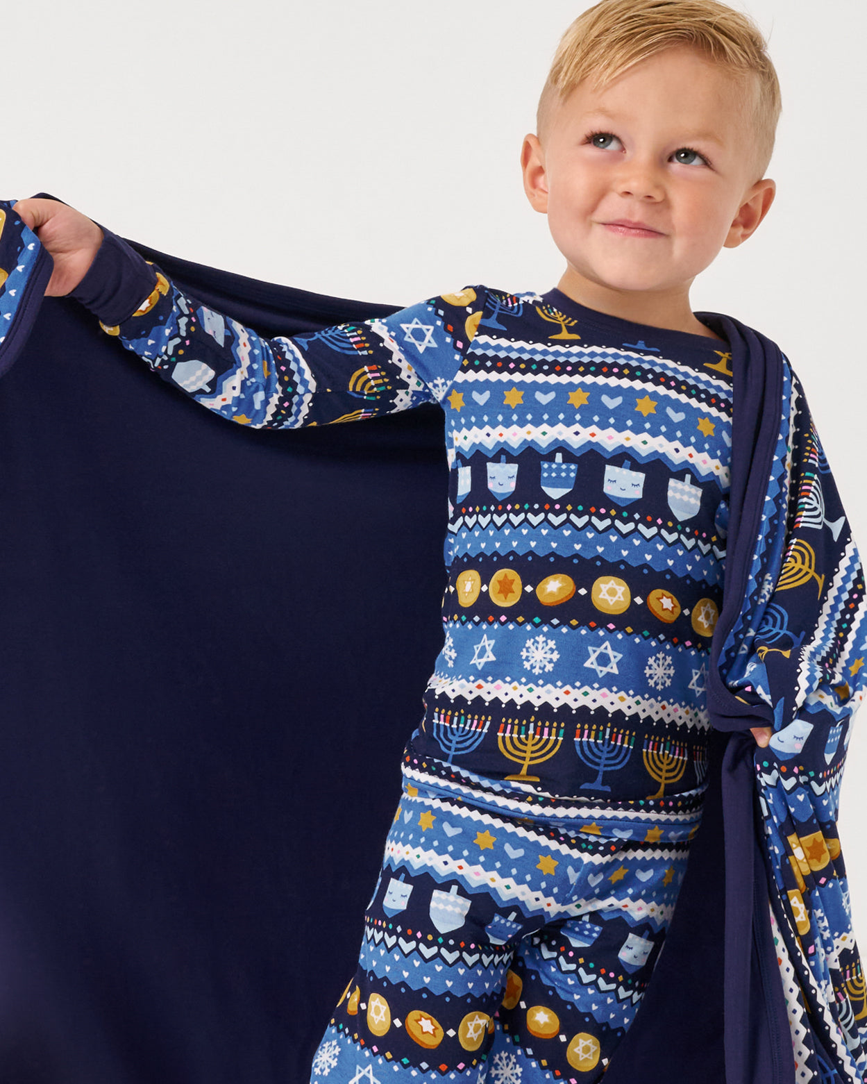 Boy holding out the Hanukkah Fair Isle Large Cloud Blanket® showing the solid blue side