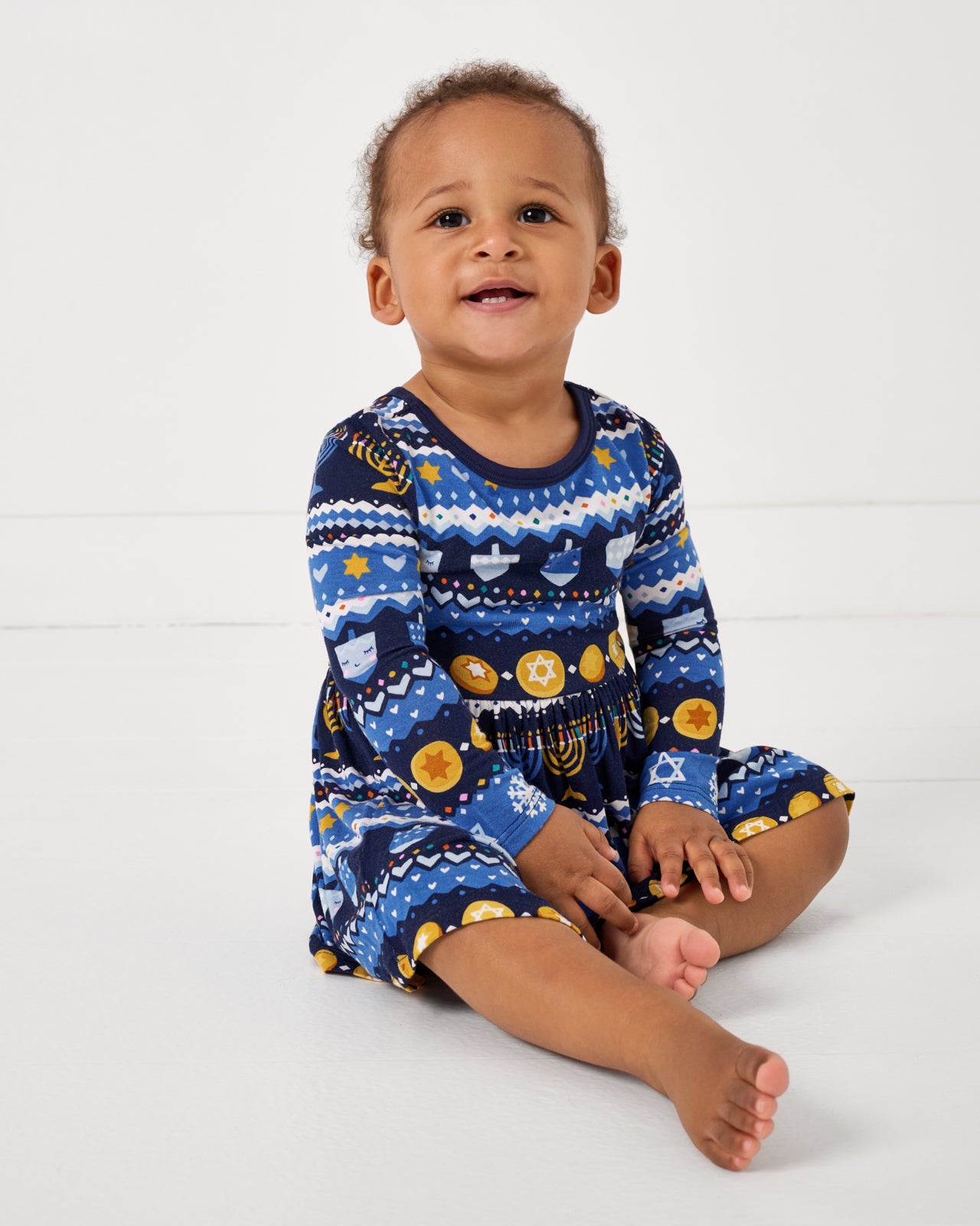 Sitting baby wearing the Hanukkah Fair Isle Skater Dress with Bodysuit