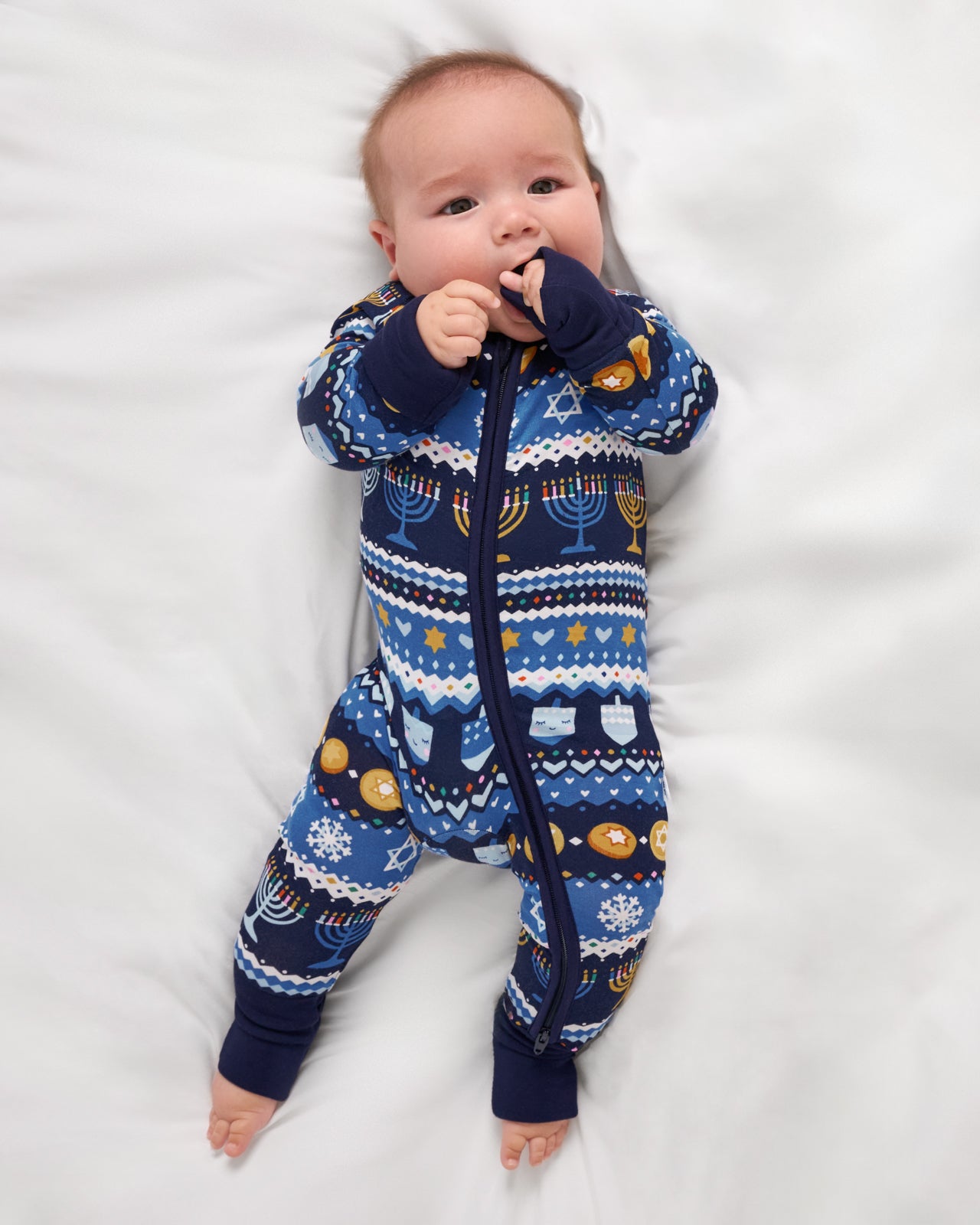 Aerial view of baby wearing the Hanukkah Fair Isle bamboo zipper pajamas