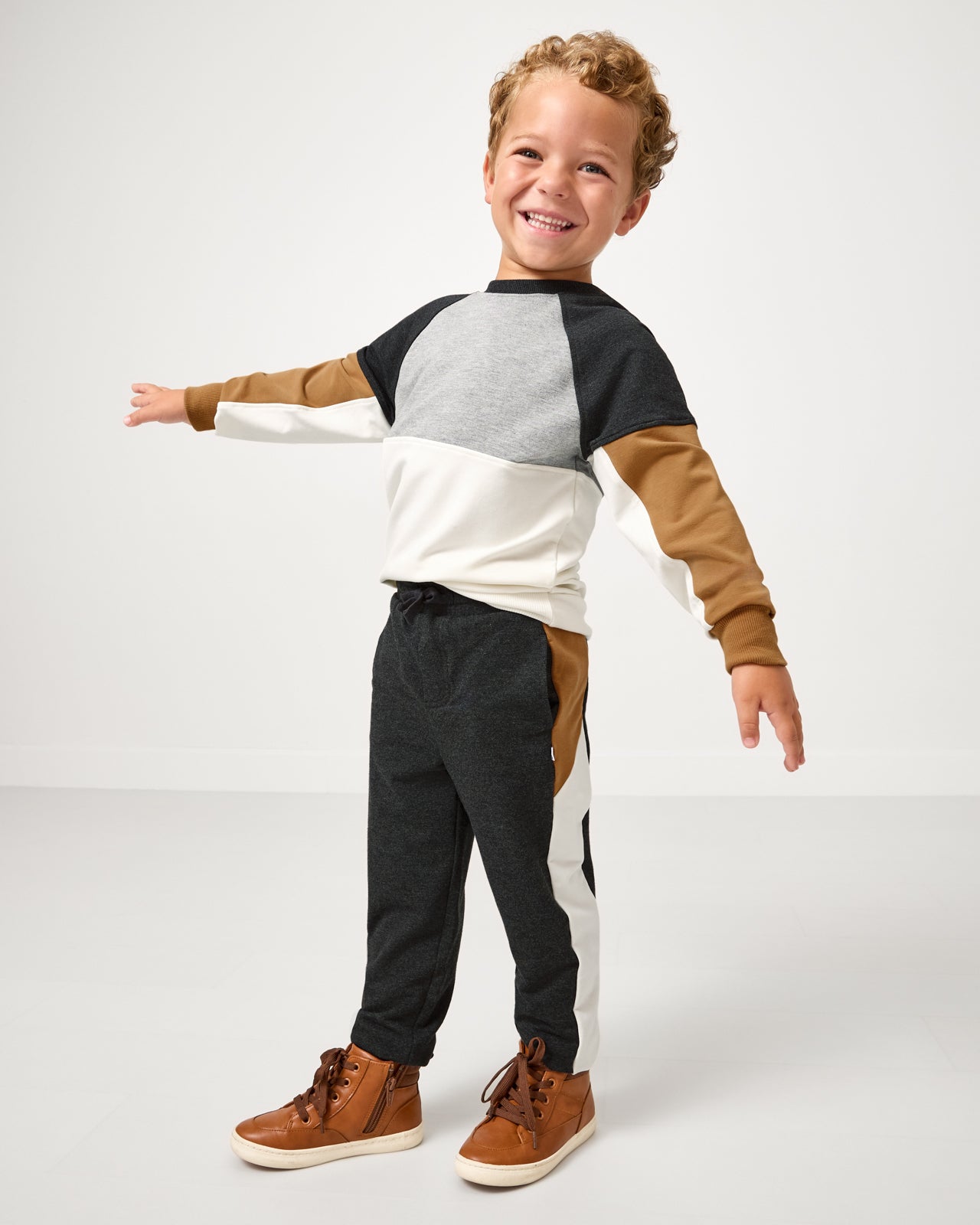 Posing boy wearing the Heather Black Panel Jogger and Crewneck