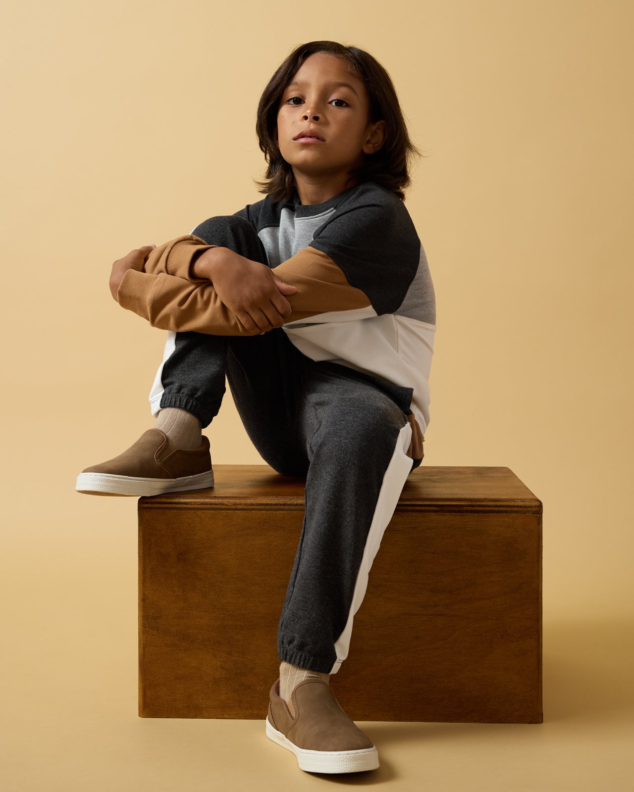 Child sitting on a wooden box wearing the Heather Gray Panel Crewneck