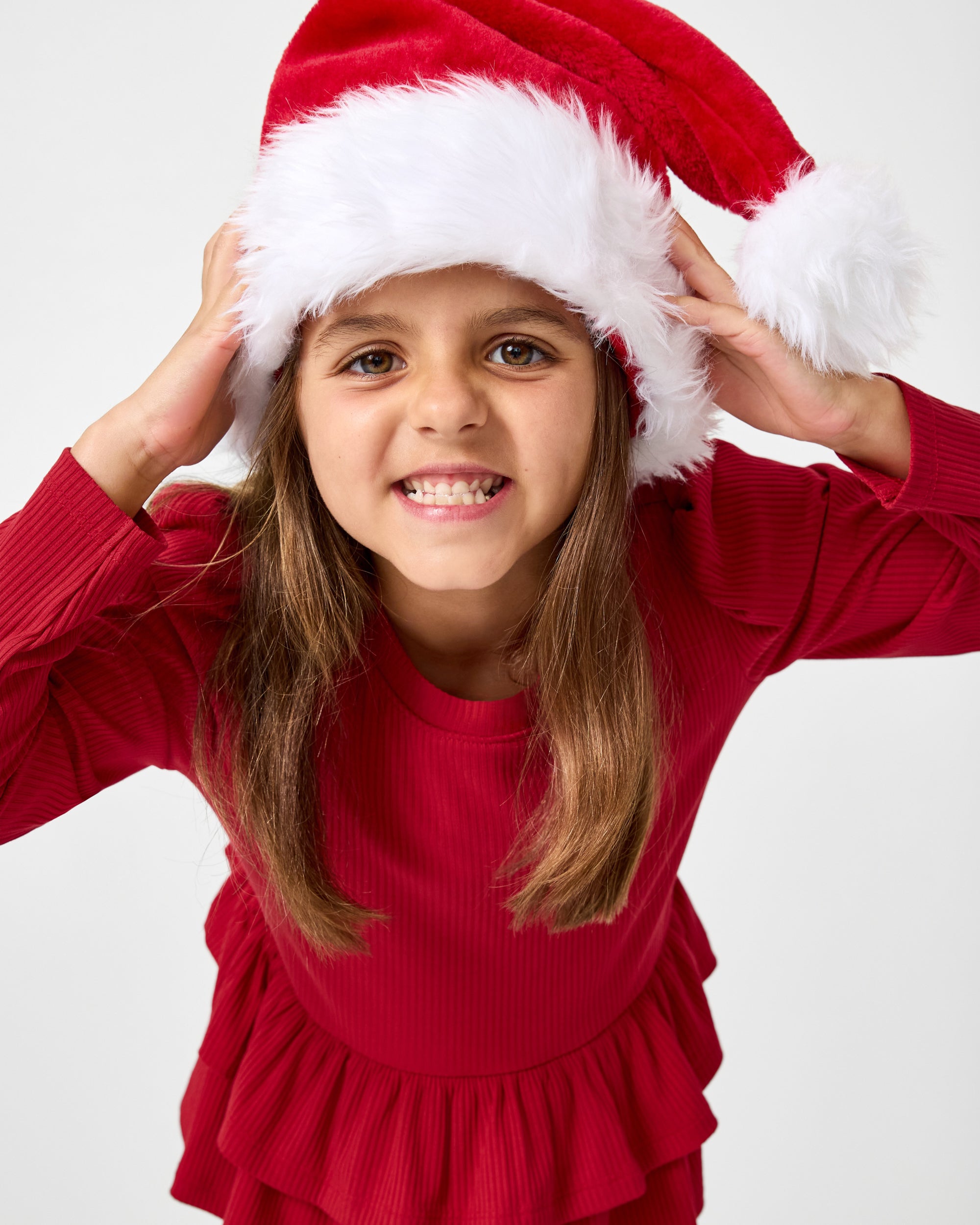 Girl wearing the Holiday Red Ribbed Tiered Peplum Top with a santa hat