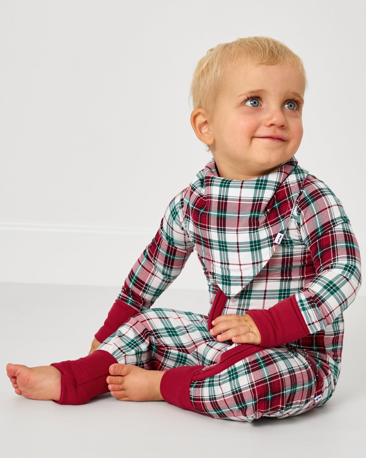 Baby wearing the Holly Plaid Bandana Bib with matching zipper pajamas