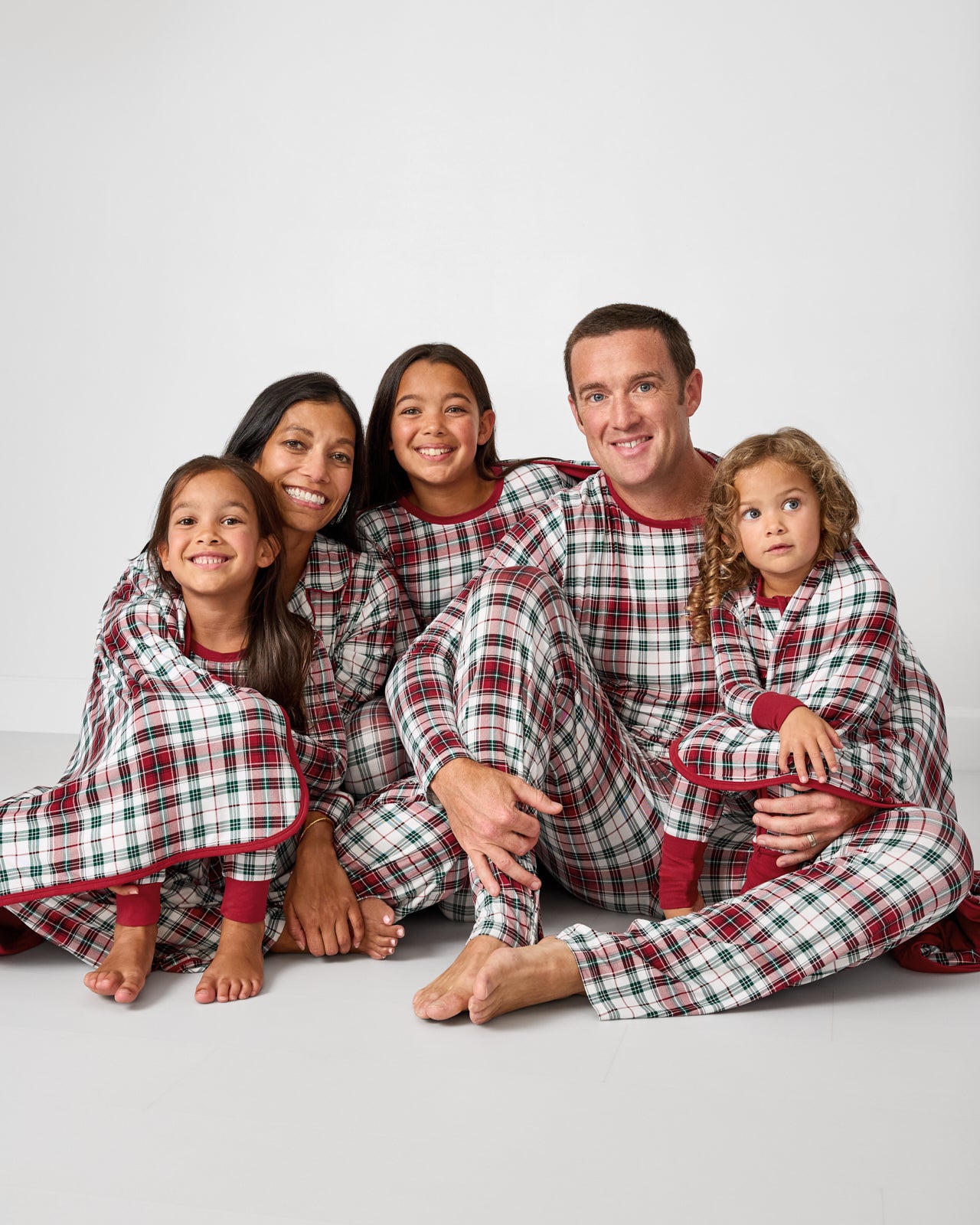Sitting family of five wrapped in the Holly Plaid Oversized Cloud Blanket®