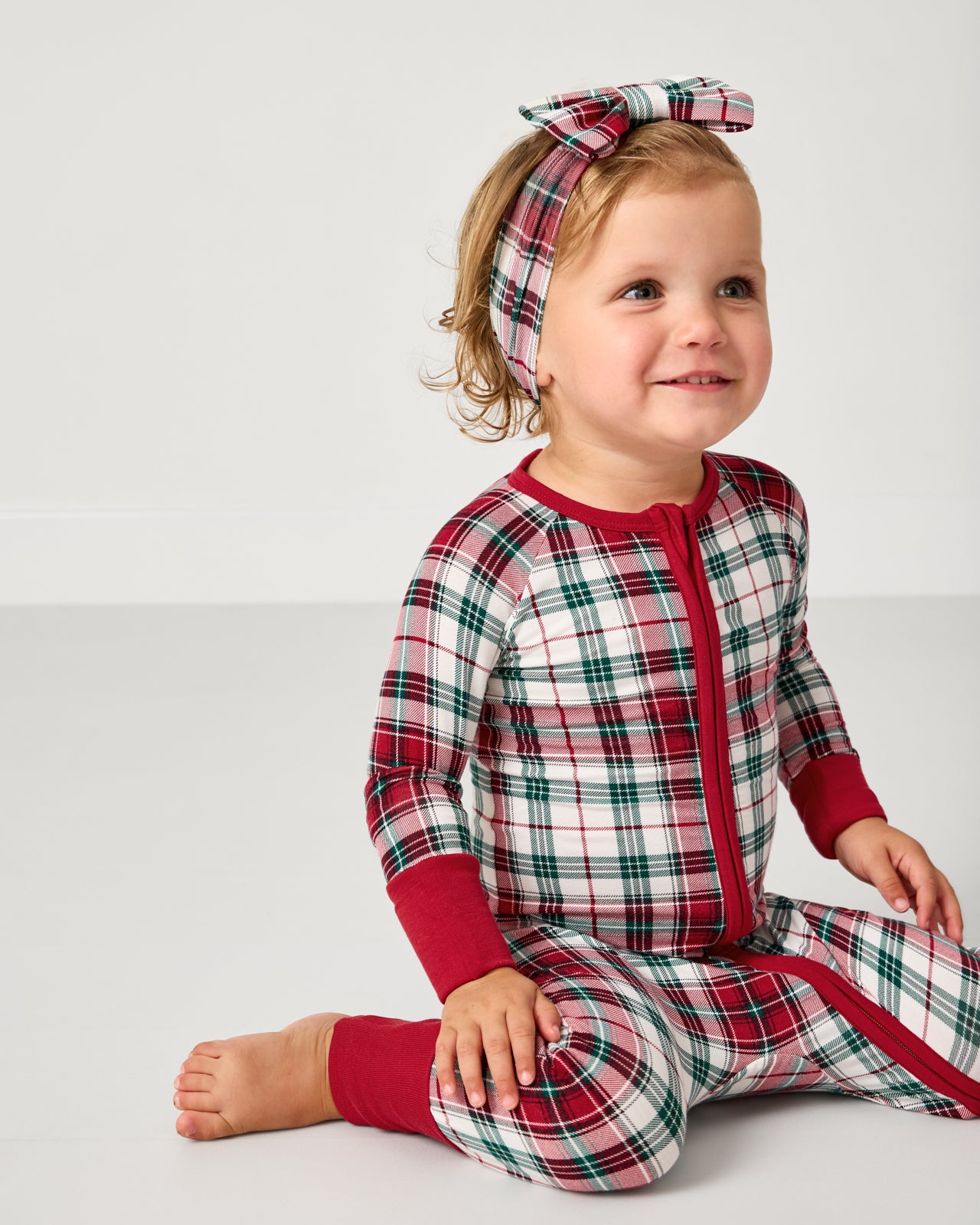 Toddler wearing the Holly Plaid Luxe Bow Headband with a matching zippy