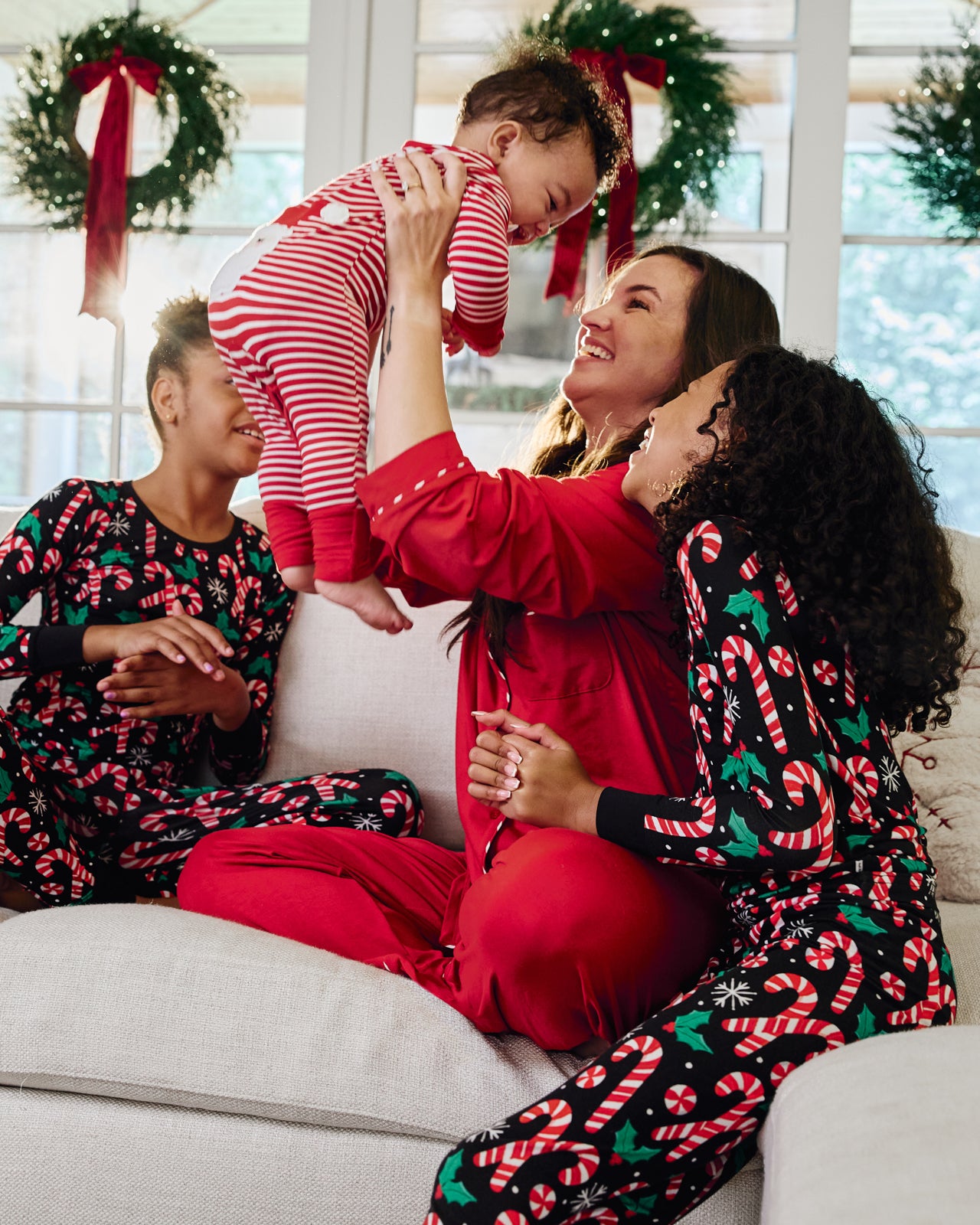 Woman holding up baby wearing the Candy Cane Stripe Crescent Zippy