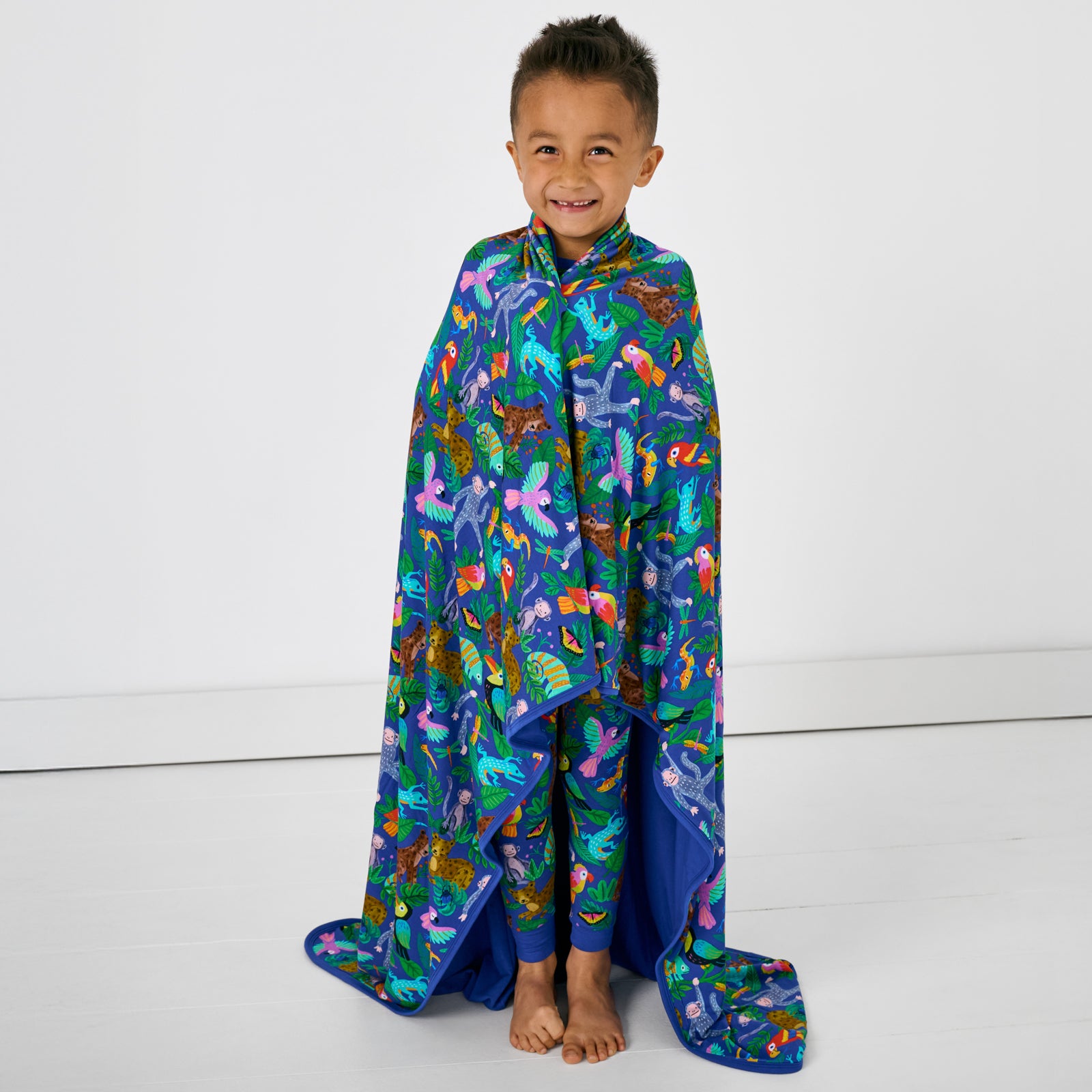 Standing child wrapped in the Treetop Tails Large Cloud Blanket®