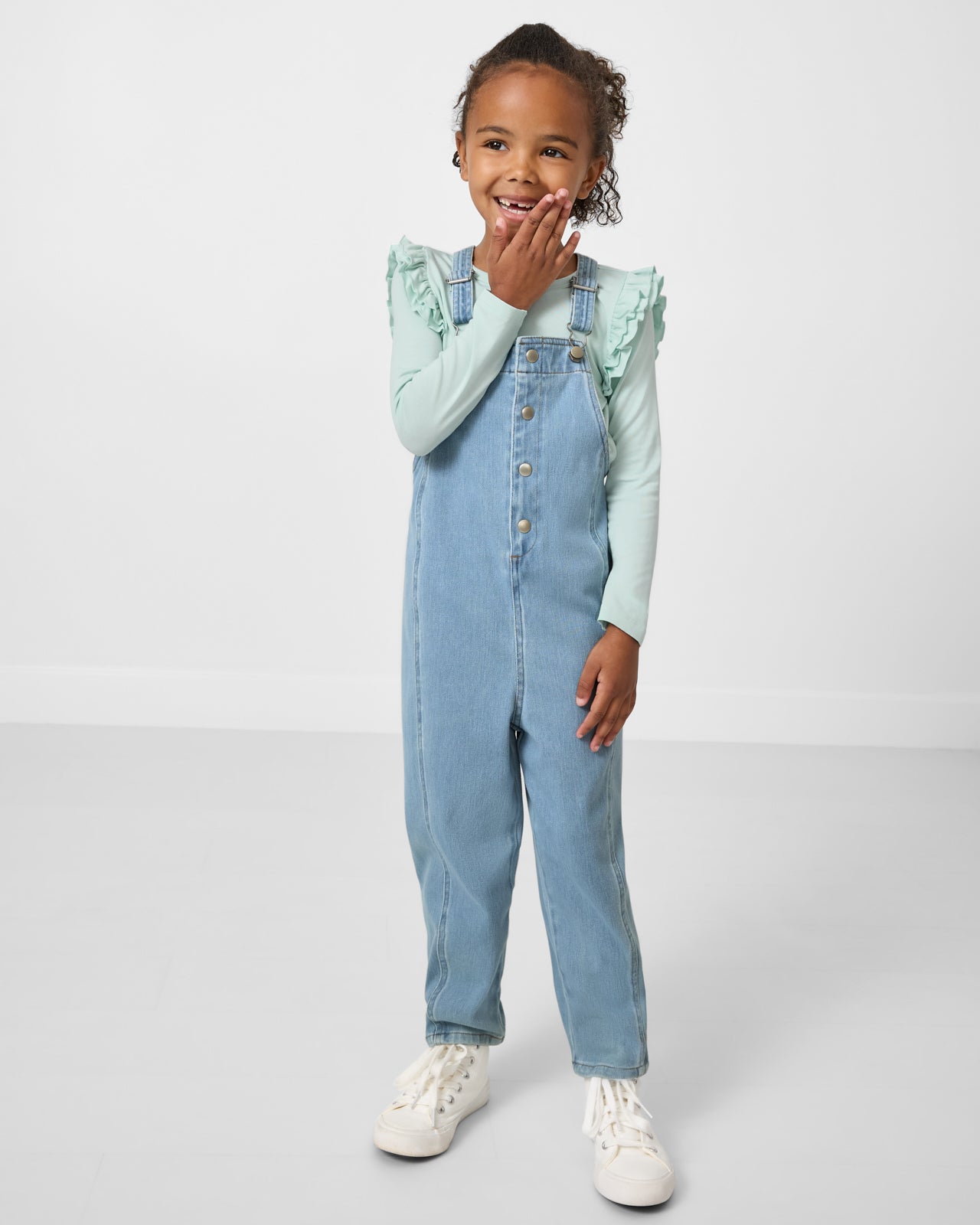 Girl wearing the Light Blue Denim Overall over a mint green tee