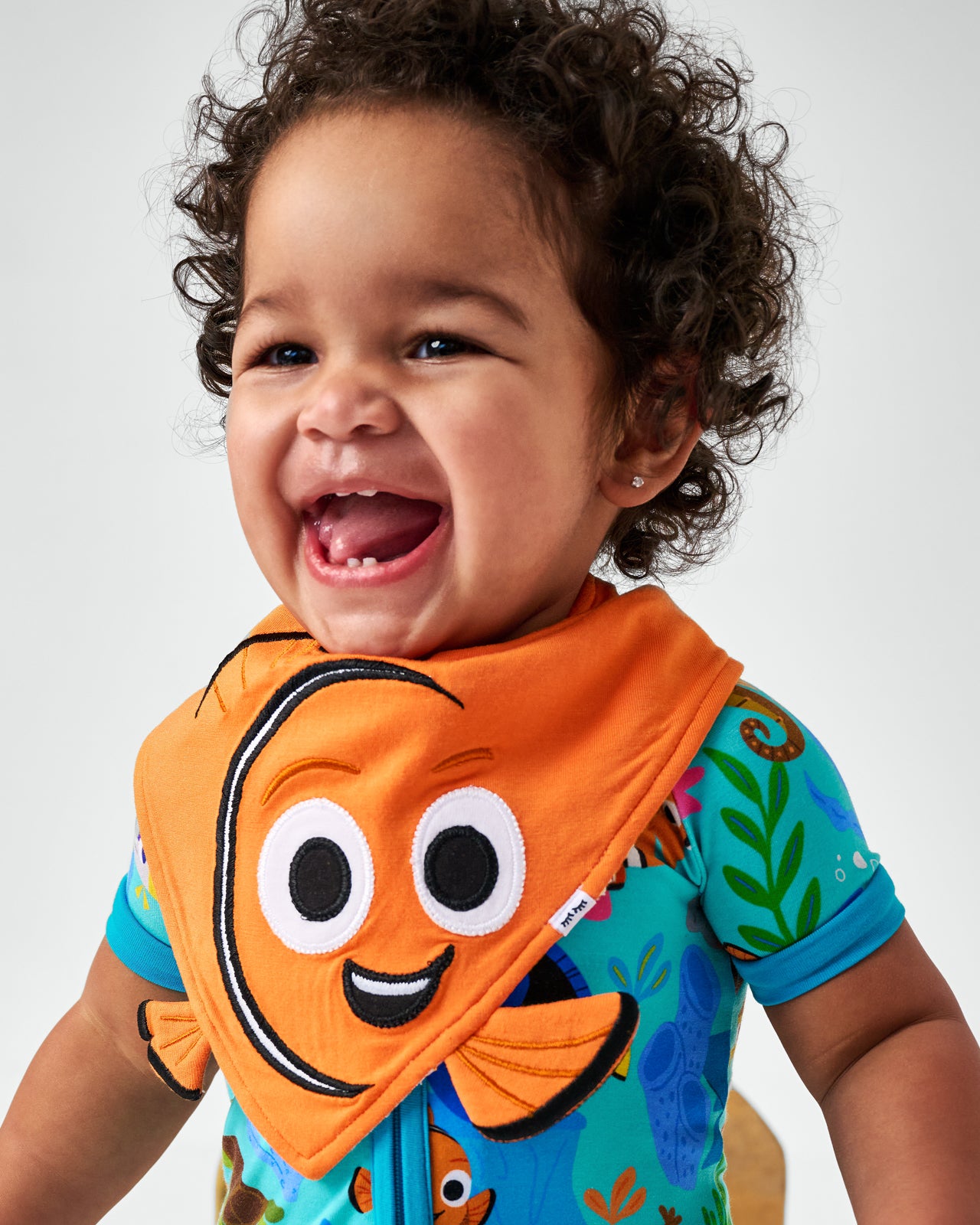 Smiling child wearing the Disney Nemo Bandana Bib with Nemo's Reef zipper pajamas