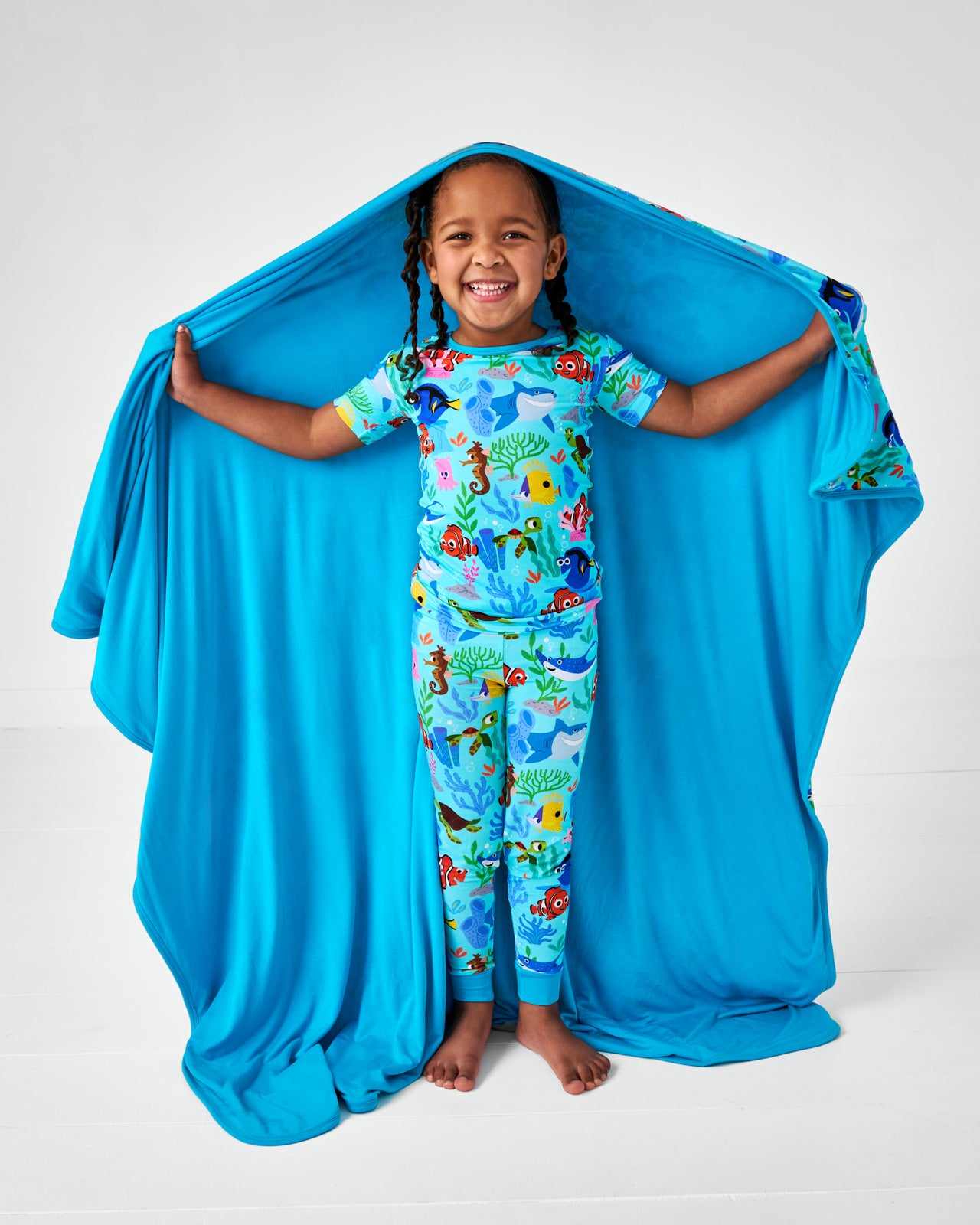 Standing child wearing Disney Nemo's Reef bamboo pajamas and holding the matching Large Cloud Blanket®