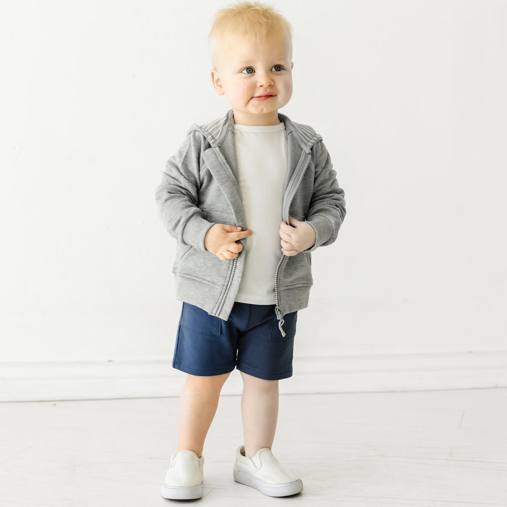 Child wearing a Heather Gray zip hoodie and coordinating Play outfit