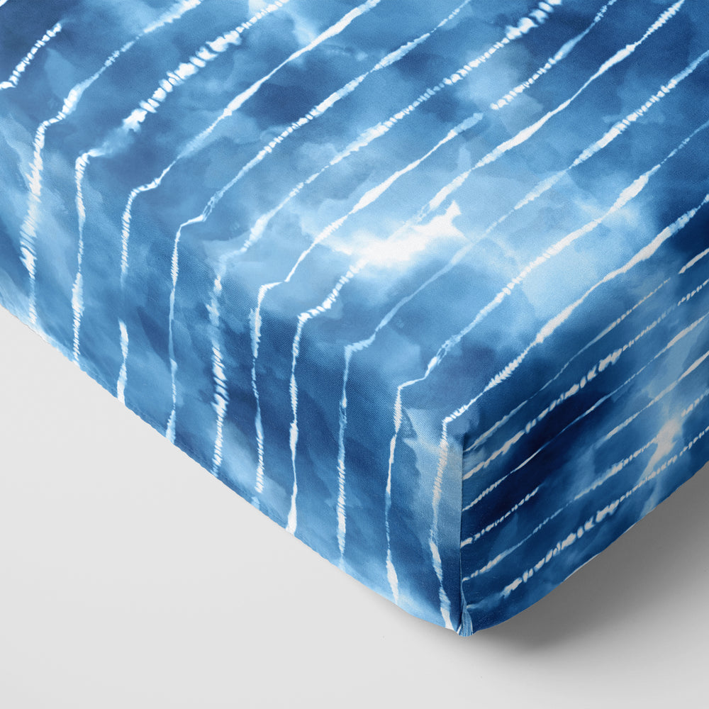 Blue Tie Dye Dreams fitted crib sheet on the corner of a mattress