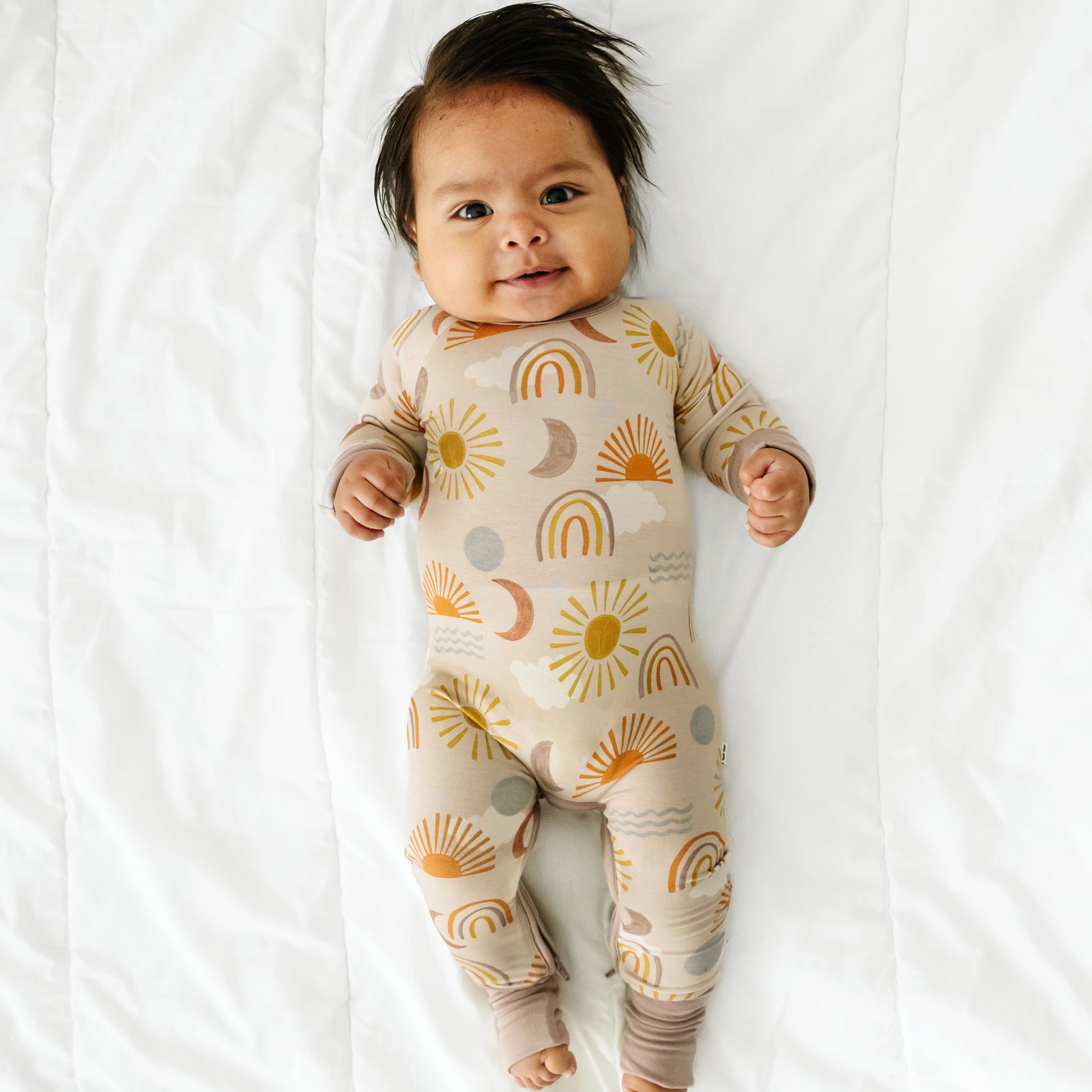 Alternate image of a child laying on a bed wearing a Desert Sunrise crescent zippy