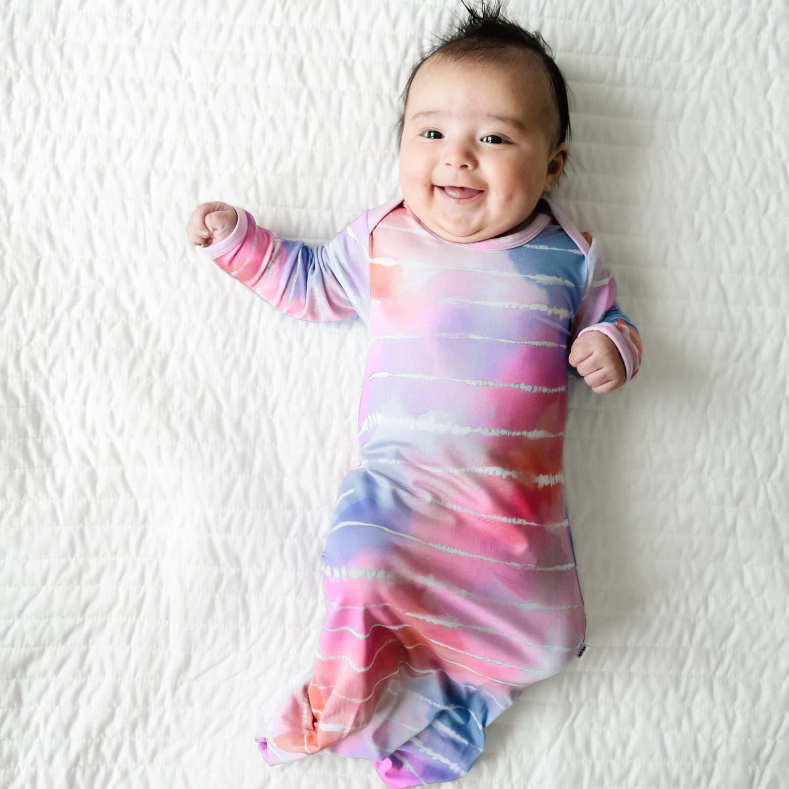 Infant laying on a blanket wearing a Pastel Tie Dye Dreams infant gown