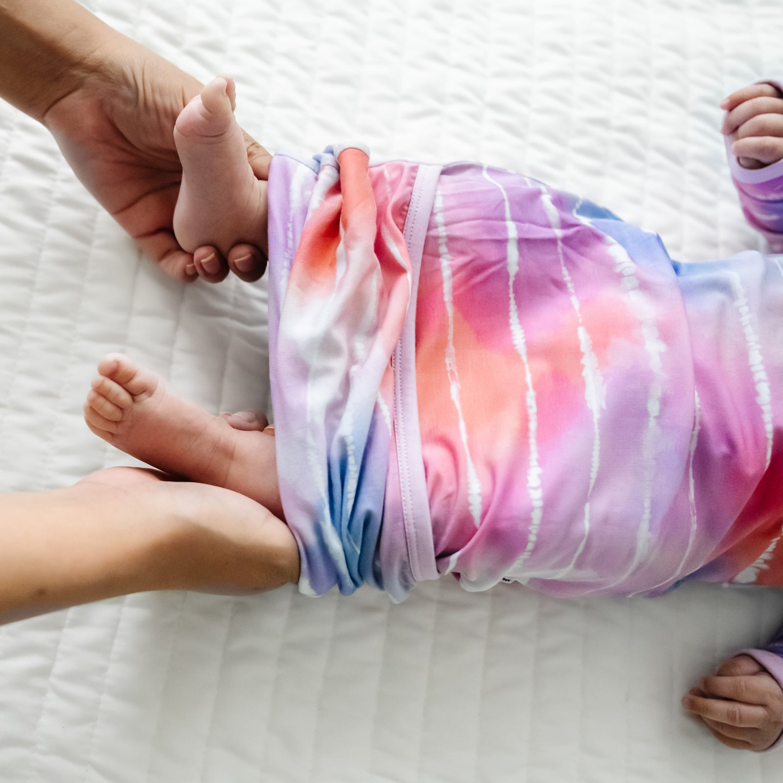 close up image of an infant wearing a Pastel Tie Dye Dreams infant gown, detailing the envelope opening on the bottom
