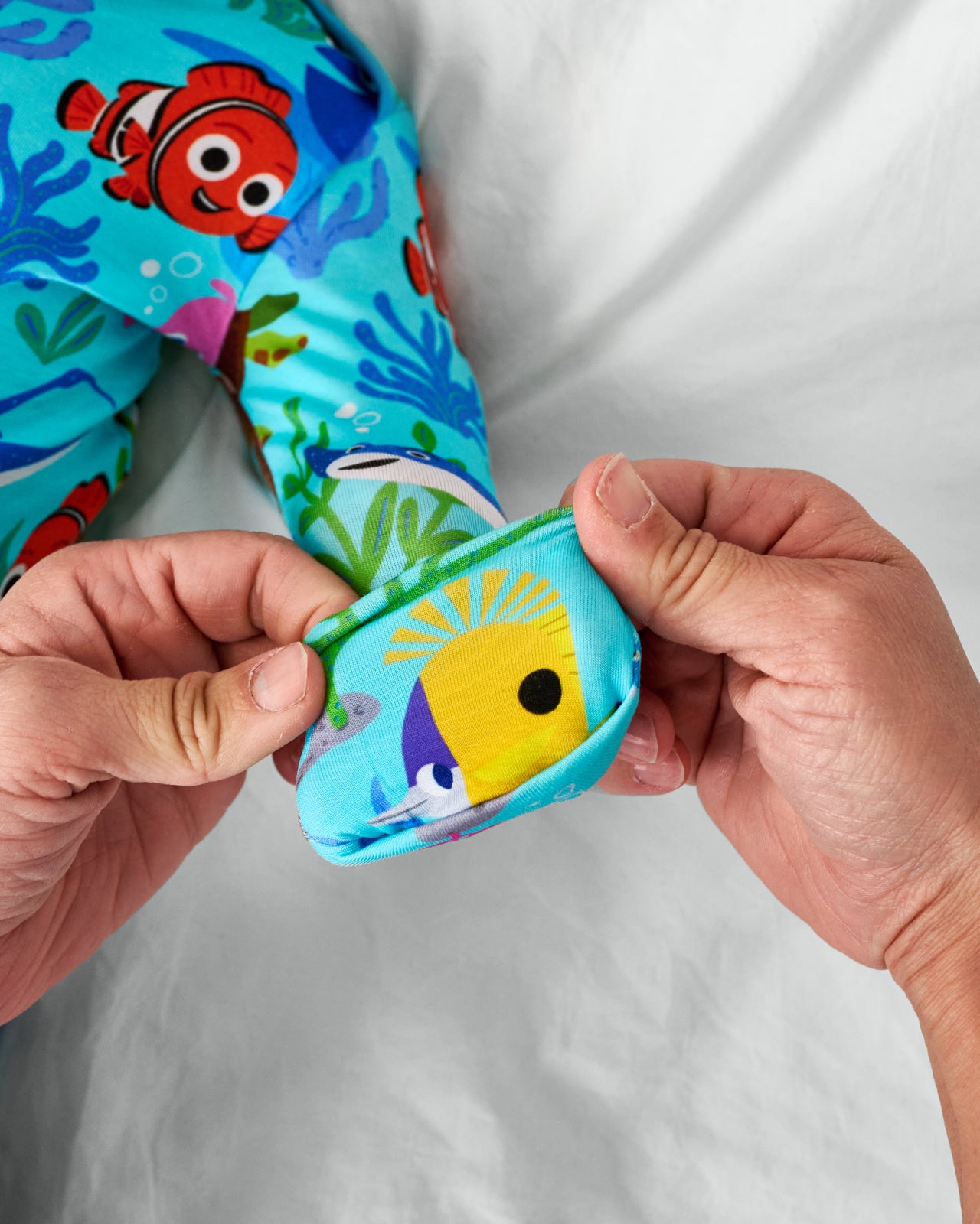 Adult demonstrating the mittens on the Pixar Nemo's Reef Infant Gown