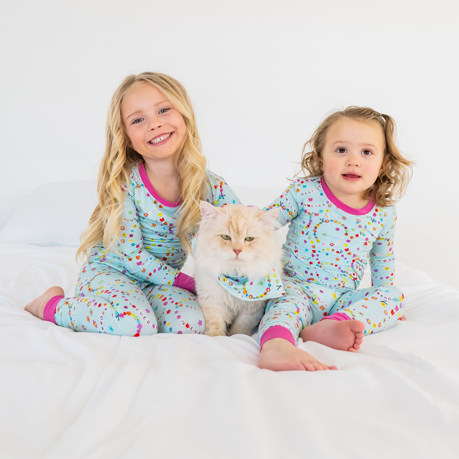 Two children and a cat wearing matching Friends Forever pajamas