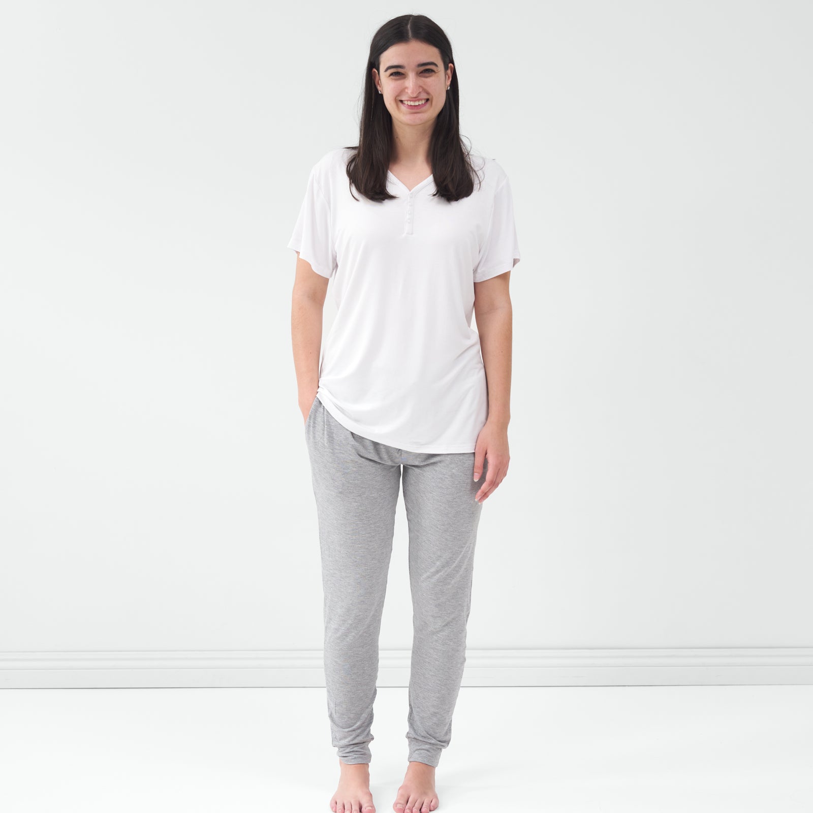 Standing woman wearing the Bright White Women's Short Sleeve Pajama Top with gray pajama pants