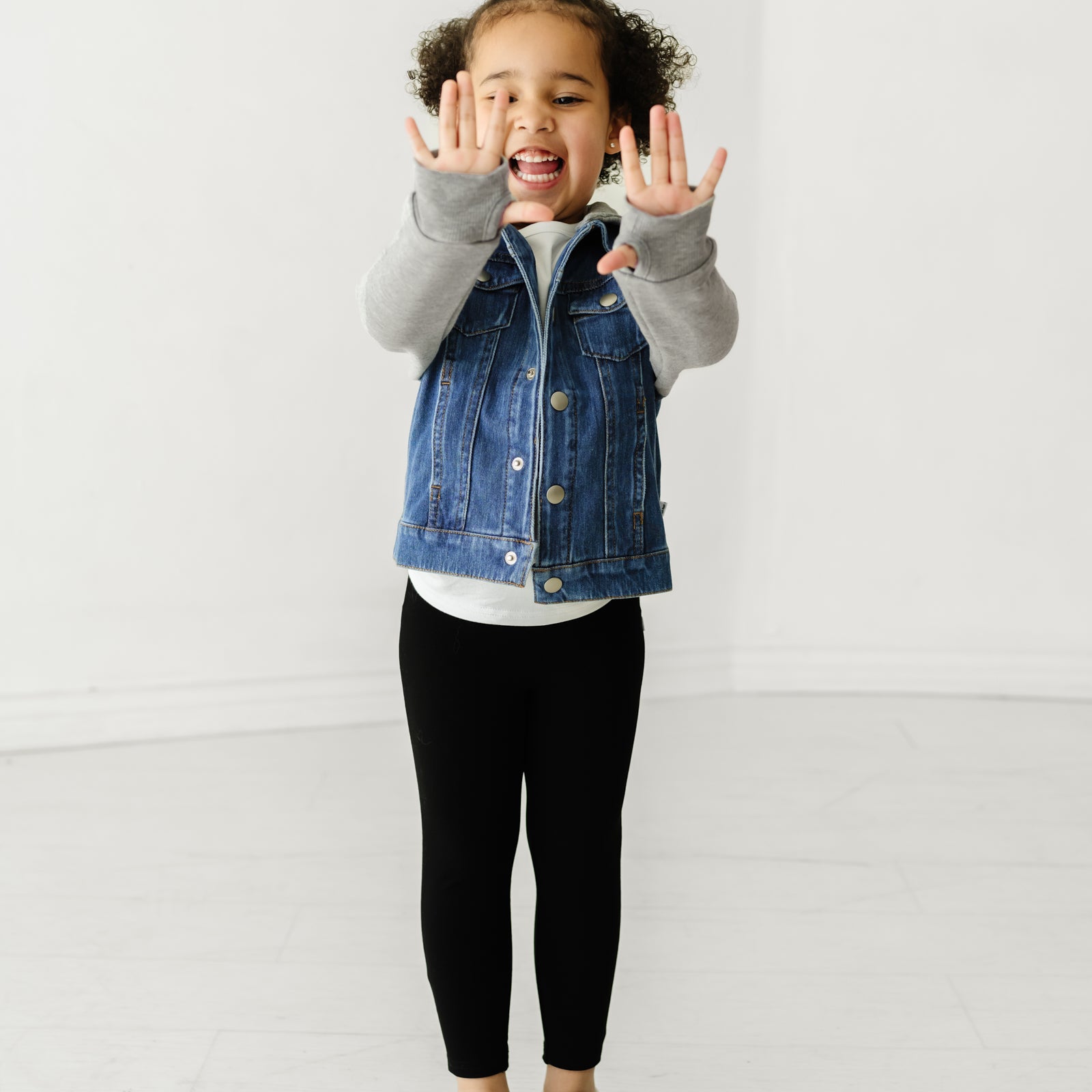 Child wearing a Midwash Blue Denim jacket and coordinating Play outfit showing the thumbholes on the jacket sleeve cuffs