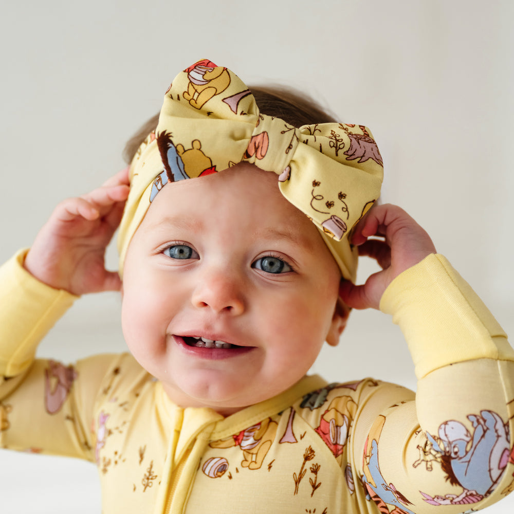 Close up image of a child wearing a Playtime with Pooh luxe bow headband