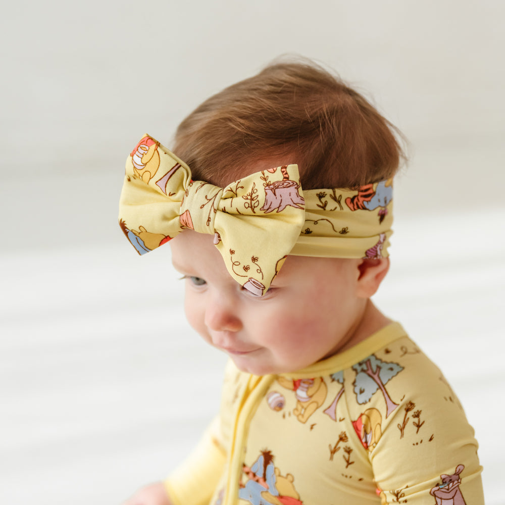 Close up image of a child wearing a Playtime with Pooh luxe bow headband with a focus on the profile of the bow