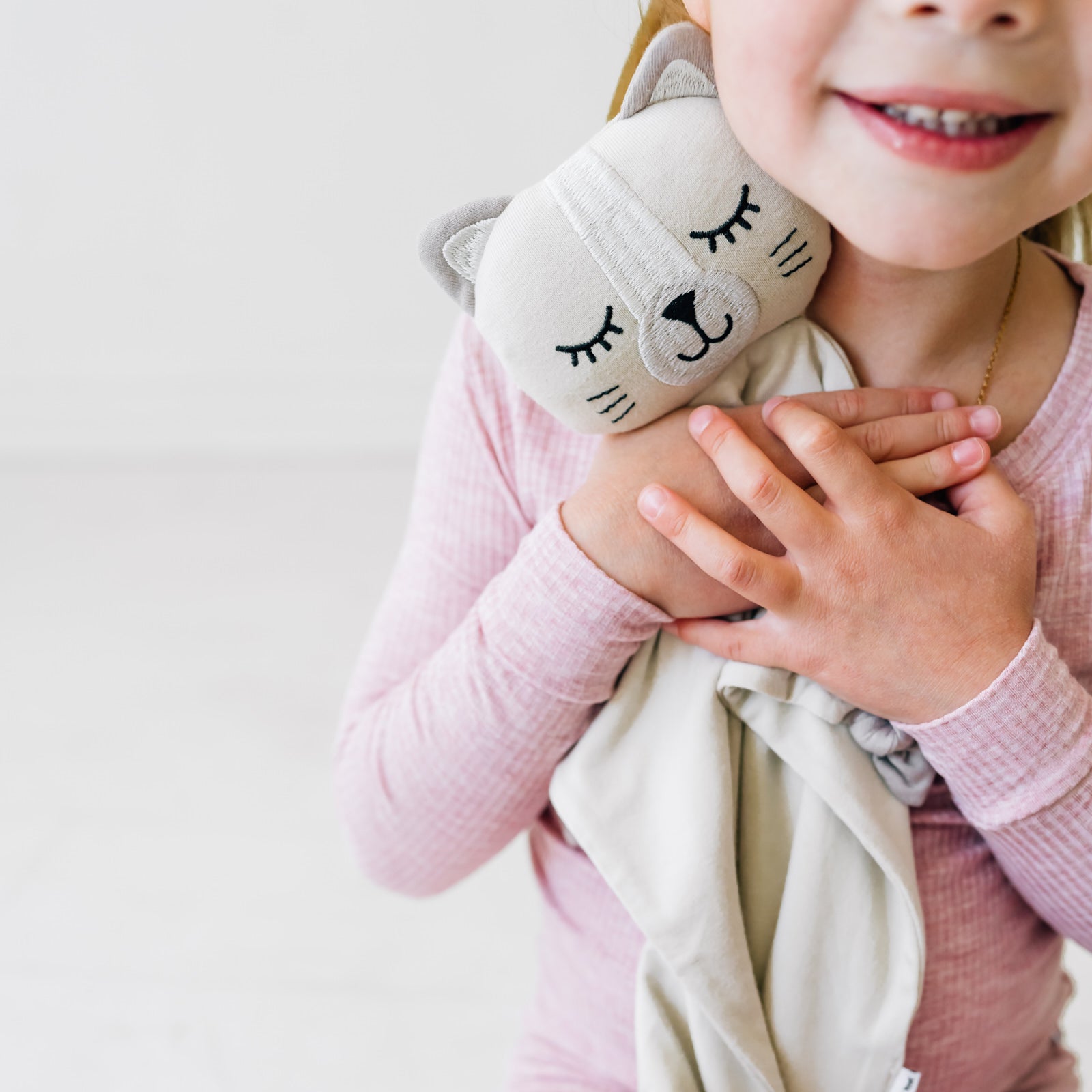 Close up image of a child hugging a Clementine the Cat lovey