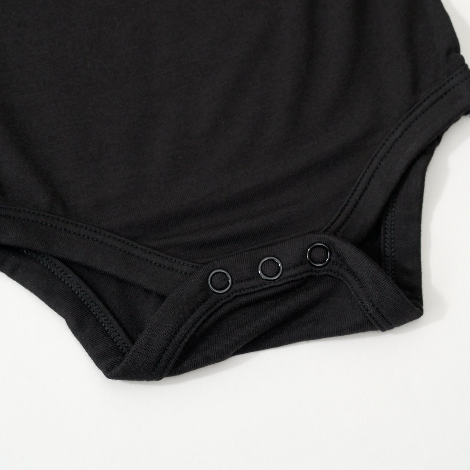 Close up flat lay image of the snap detail on the Black Long Sleeve Bodysuit