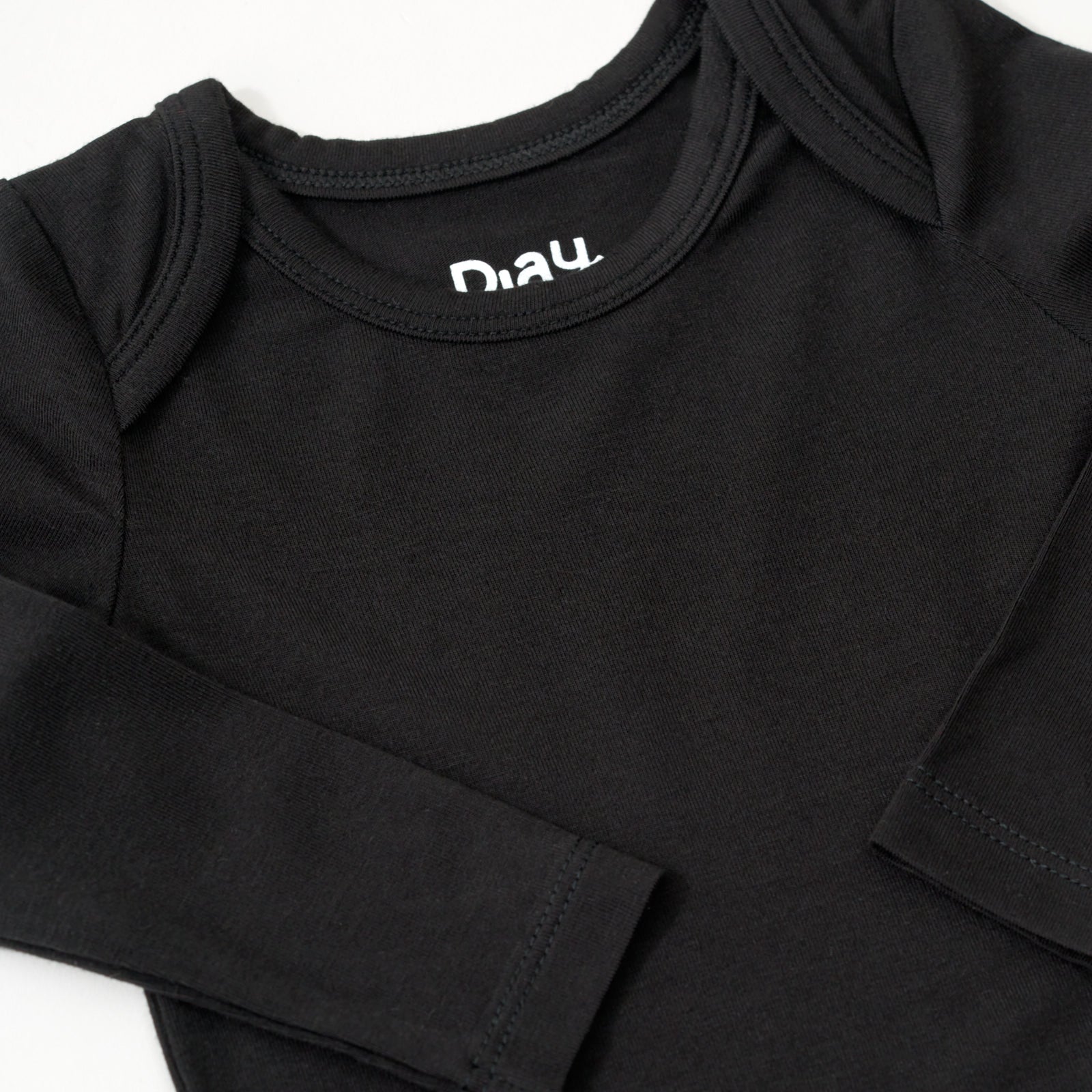 Close up flat lay image of the shoulder and sleeve details on the Black Long Sleeve Bodysuit