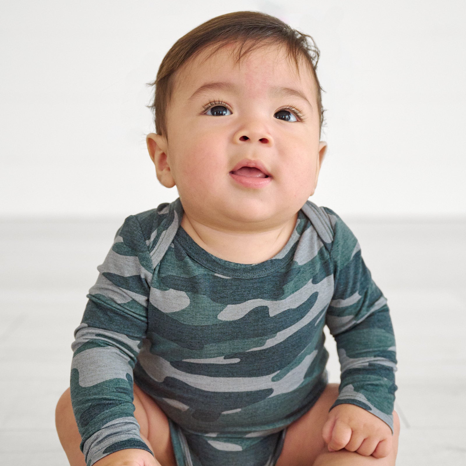Close up image of the shoulder detail , while baby wears a Vintage Camo Long Sleeve Bodysuit