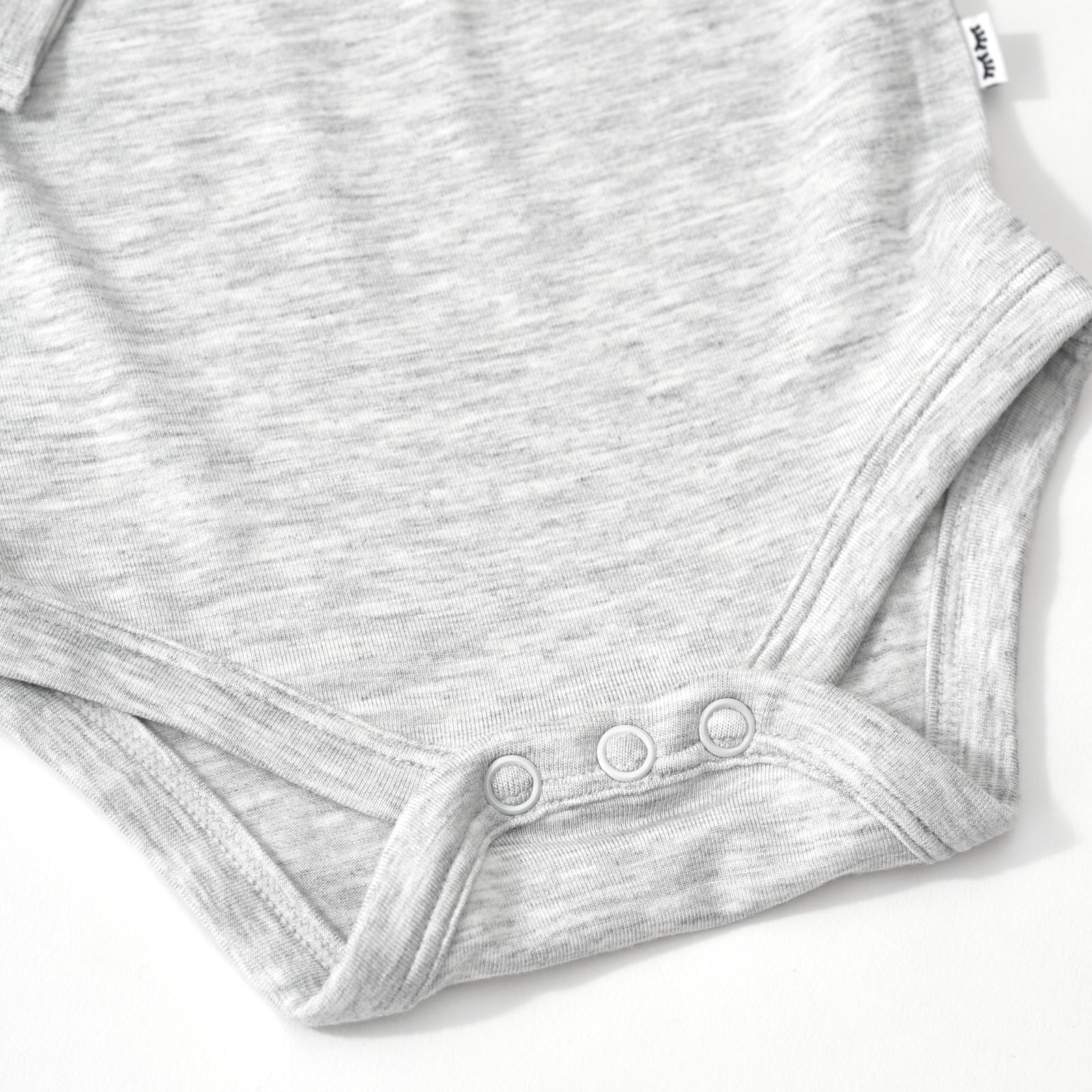 Close up flat lay of the snap detail on the Light Heather Gray Long Sleeve Bodysuit
