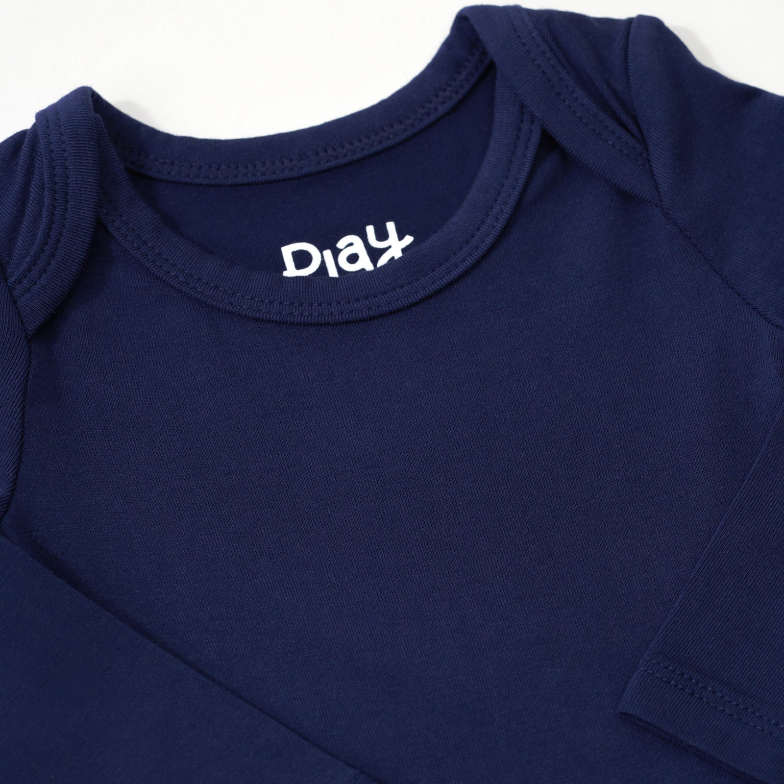 Close up flat lay image of the shoulder detail on the Classic Navy Long Sleeve Bodysuit