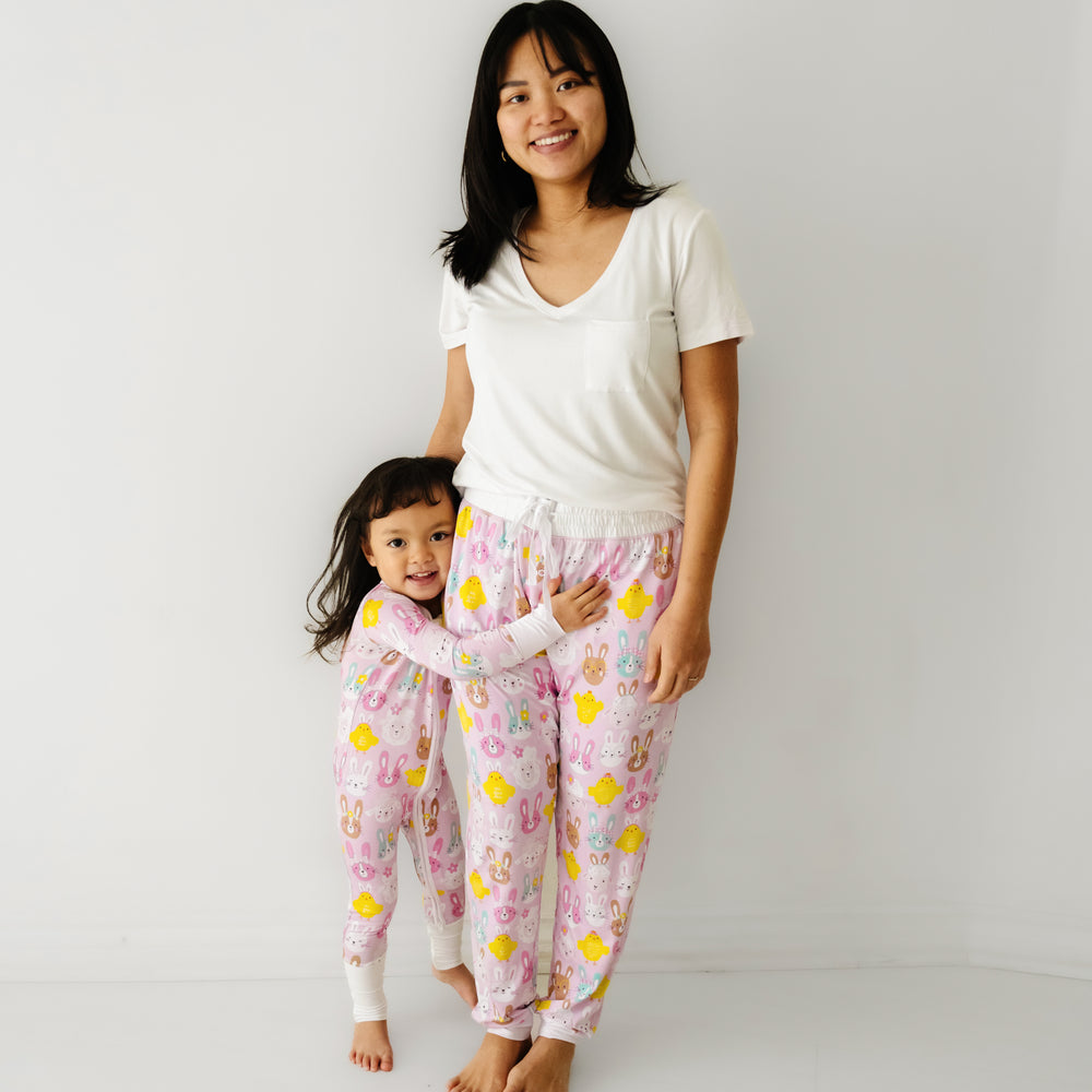 Mother posing with her daughter. Mom is wearing Pink Pastel Parade women's pajama pants paired with a coordinating Bright White women's pocket tee. Her daughters is matching wearing a Pink Pastel Parade zippy
