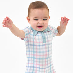 Close up image of a child wearing a Playful Plaid polo shorty romper