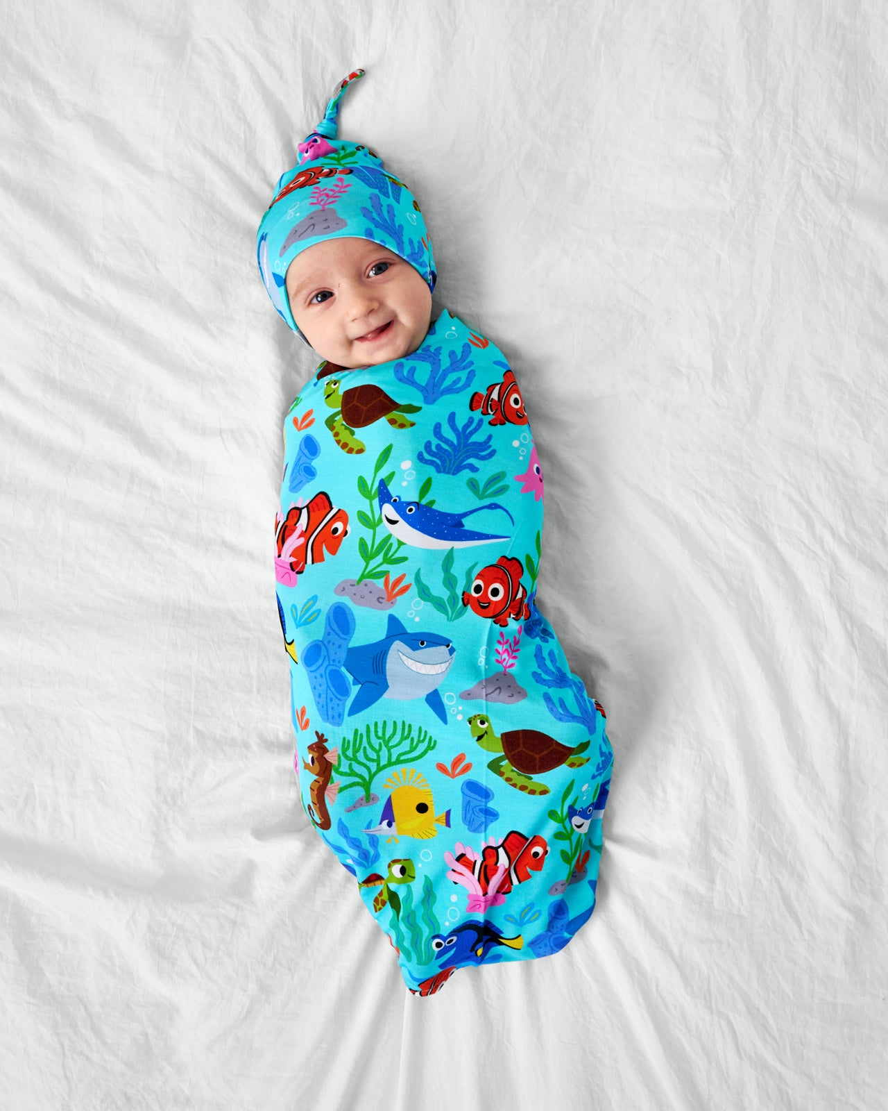 Child wearing the Disney Nemo's Reef Swaddle & Hat Set