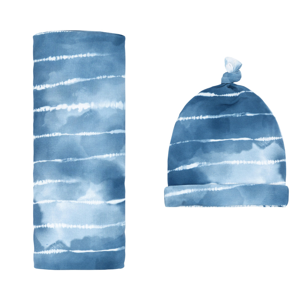 Flat lay image of a Blue Tie Dye Dreams swaddle & hat set