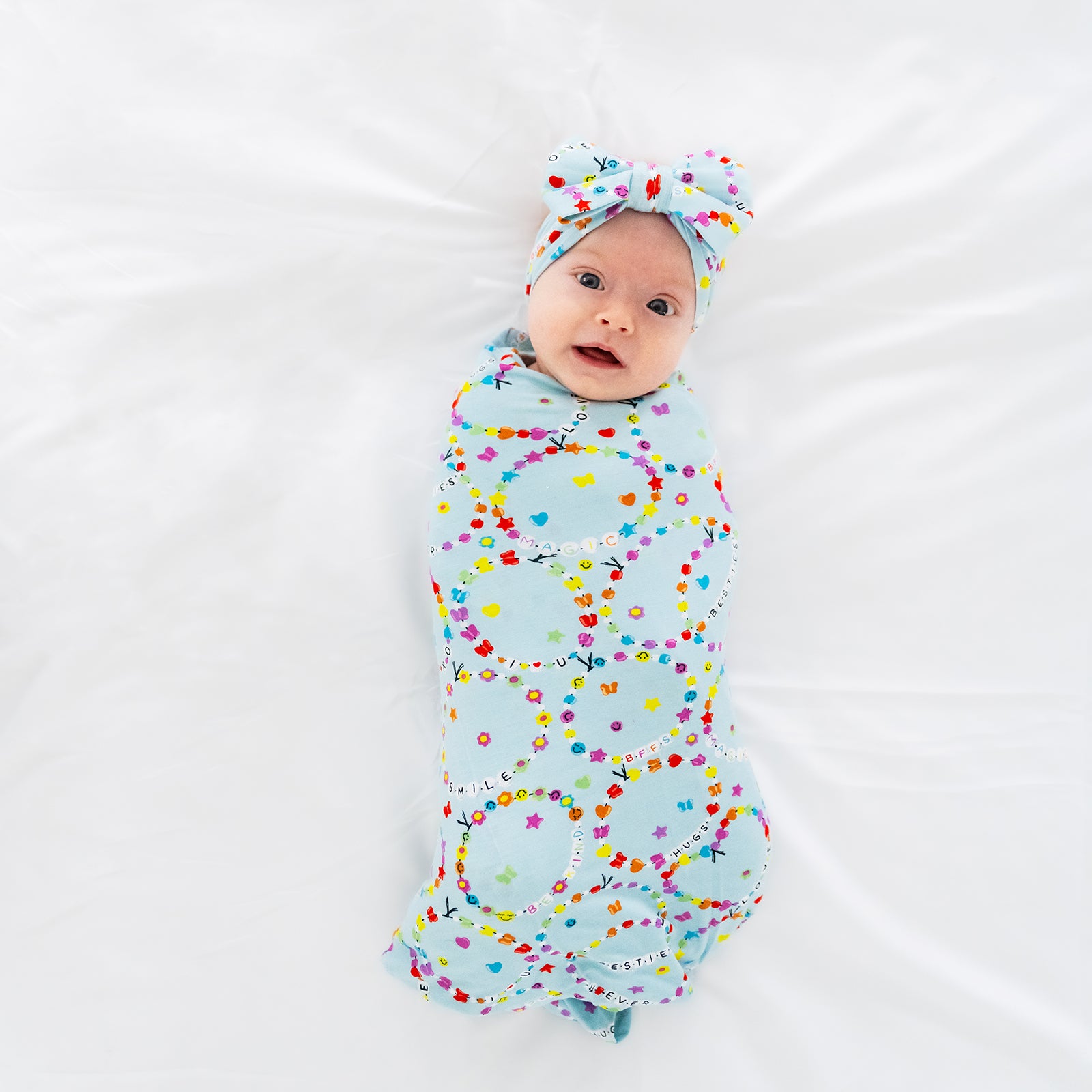 Aerial view of a child swaddled in a Friends Forever swaddle and bow set