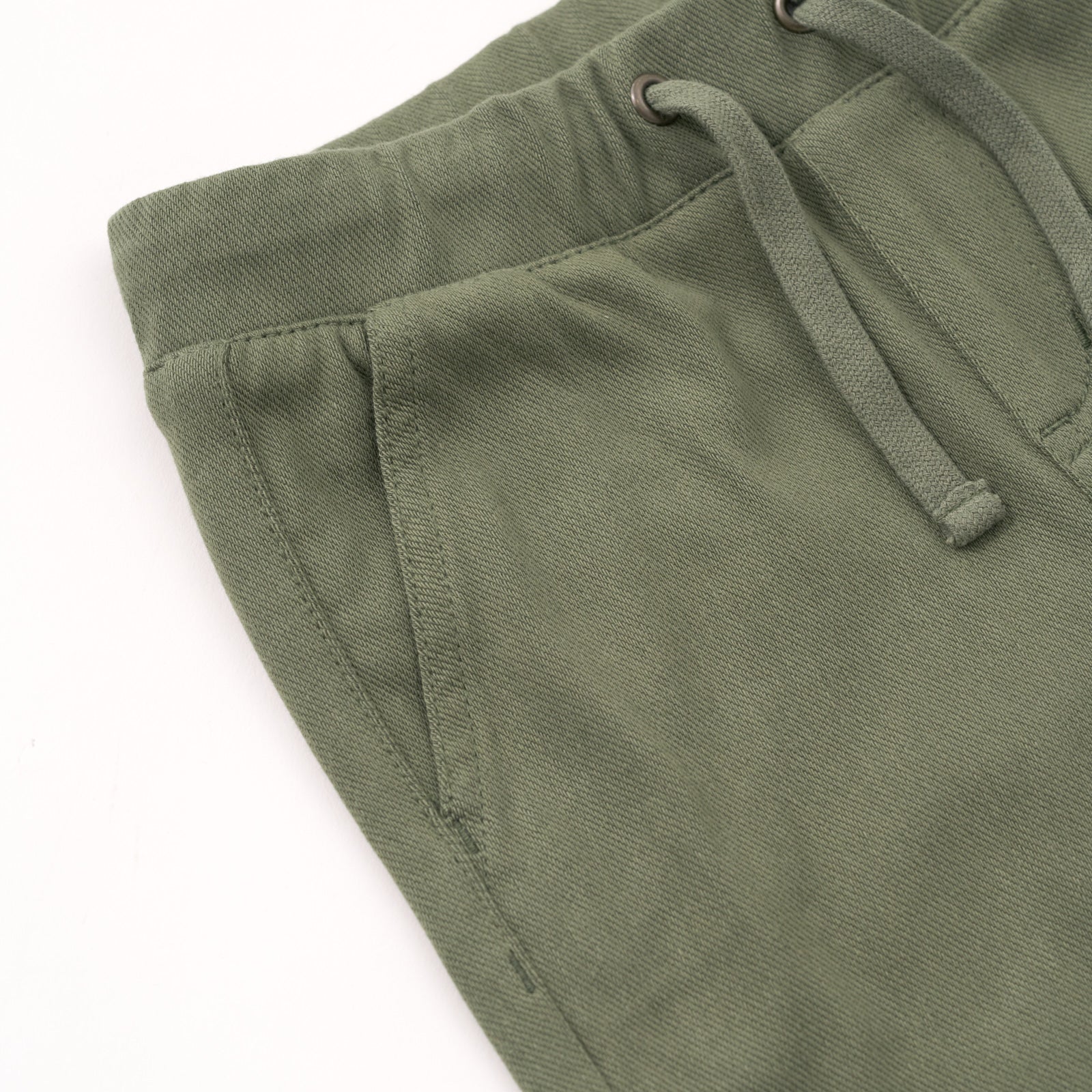 Close up flat lay of the drawstring and side pocket details on the Olive Denim Jogger