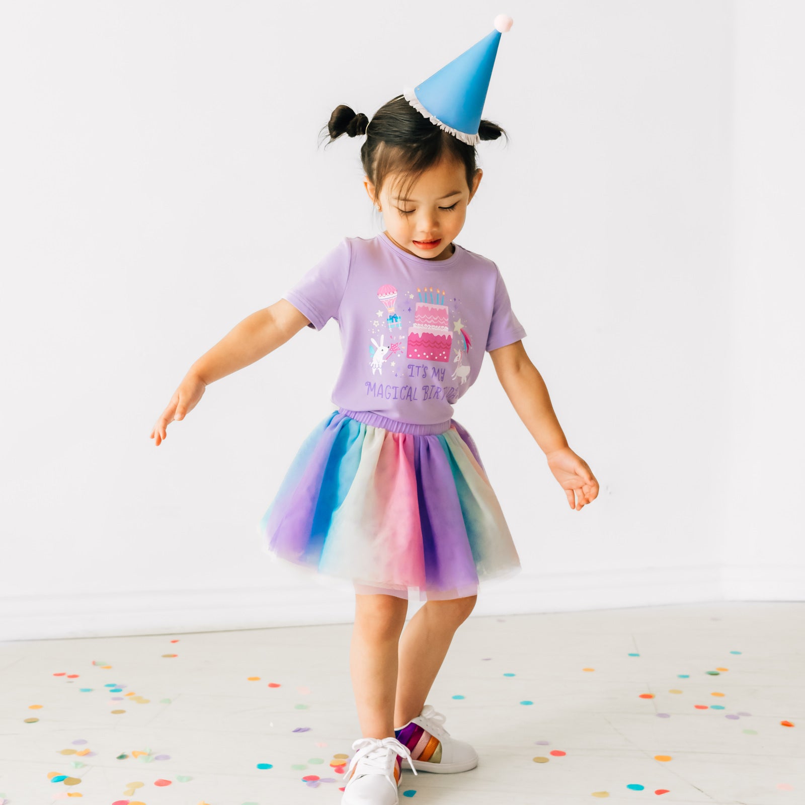 Child twirling wearing a Magical Birthday Light Lavender graphic tee paired with a rainbow tutu skirt