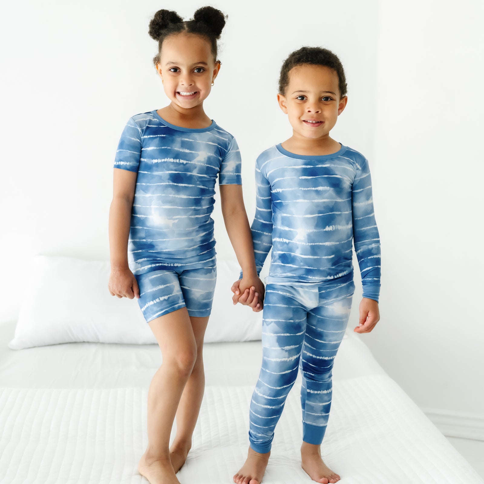 Two children holding hands wearing matching Blue Tie Dye Dreams pajamas